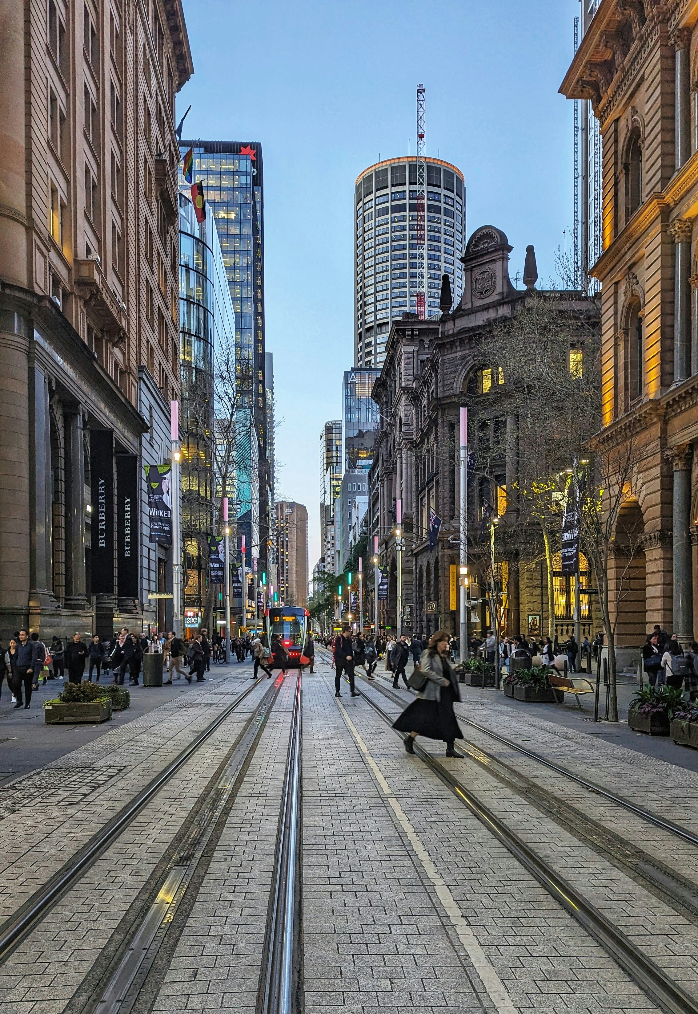 路面電車の線路や建物のある通りを歩く人々。