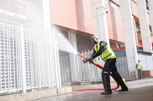Man in safety vest sprays water from hose