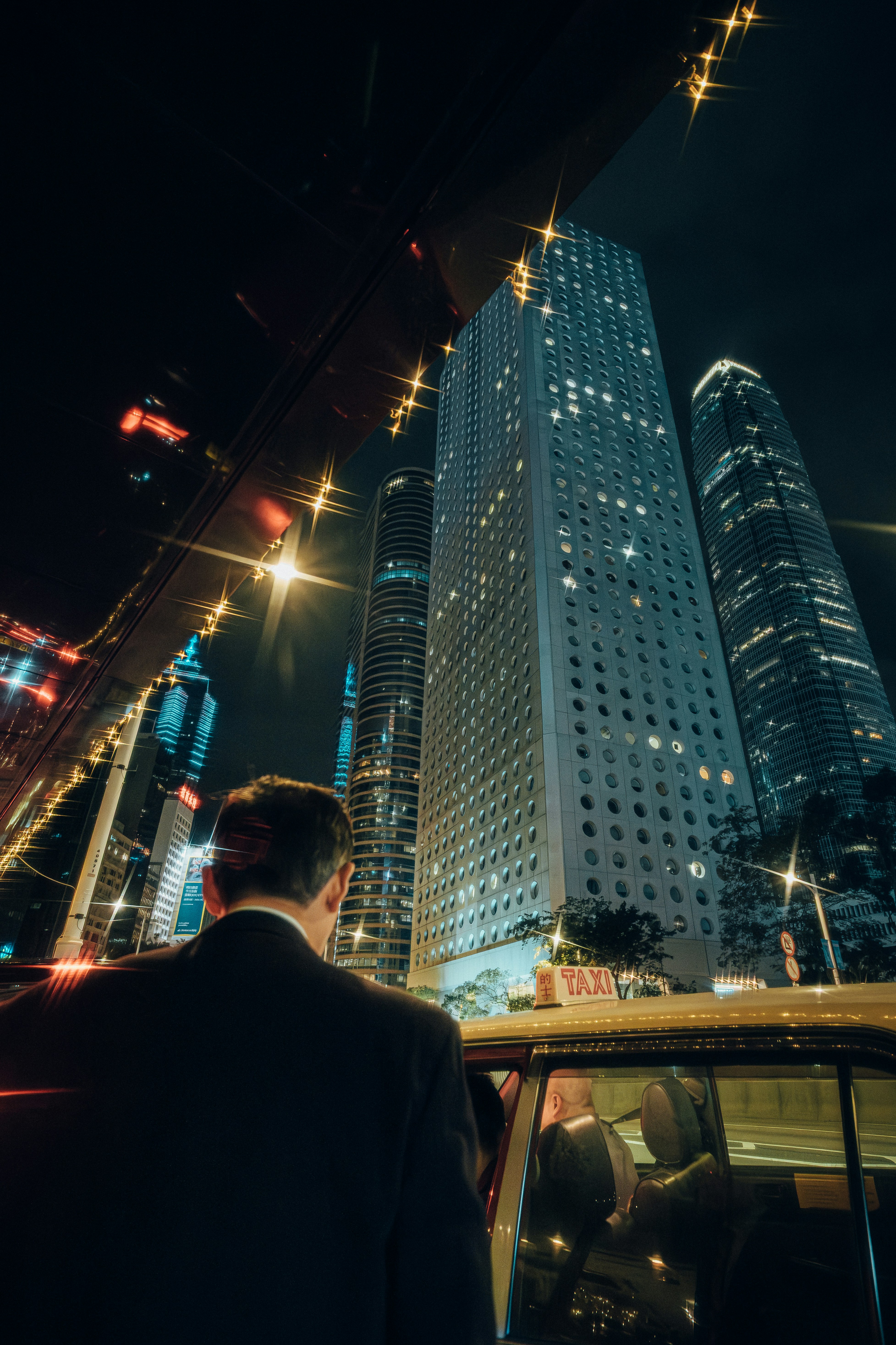 Man in suit enters taxi with city skyscrapers at night