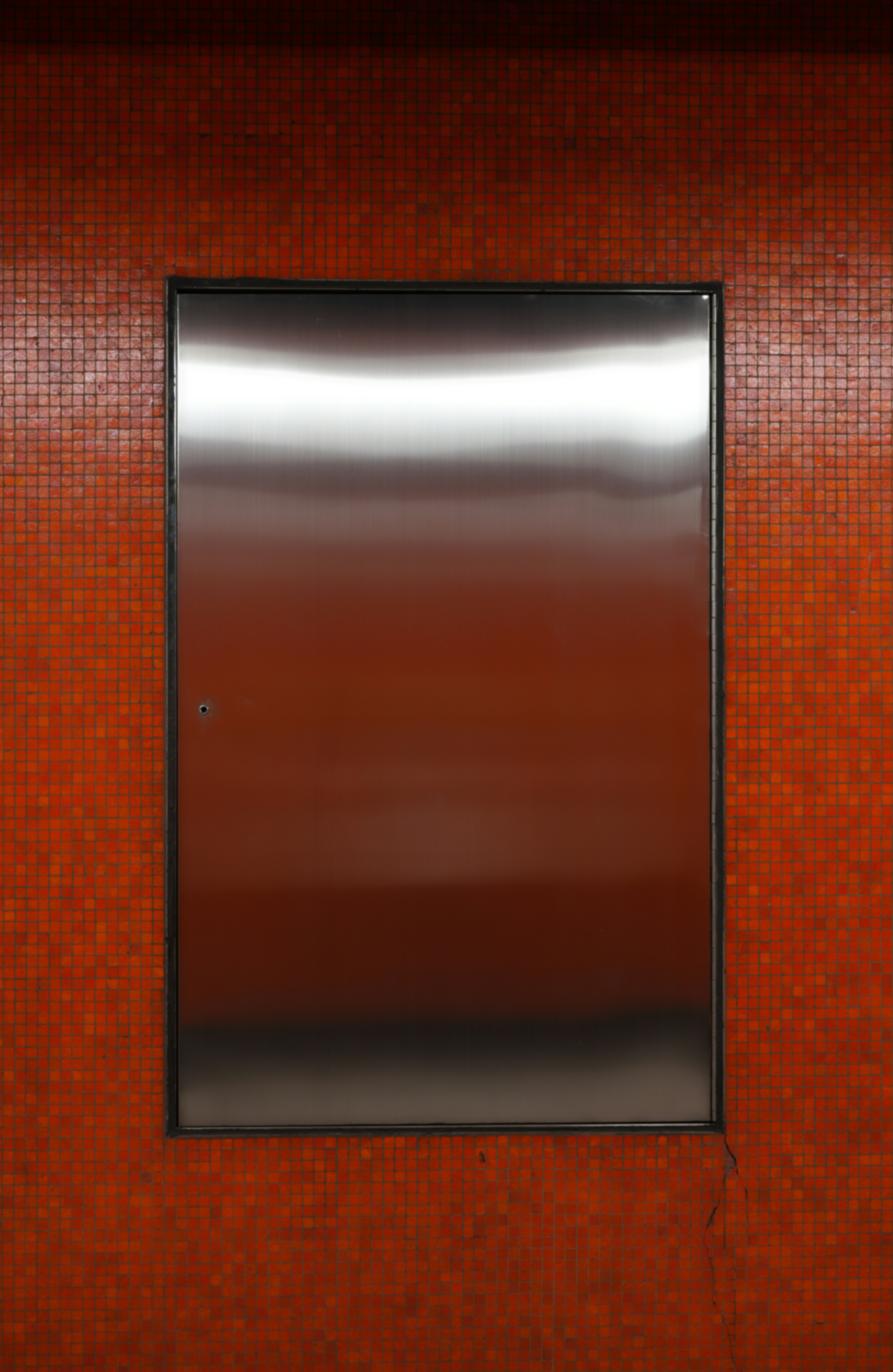 A metallic door set in a mosaic tiled wall