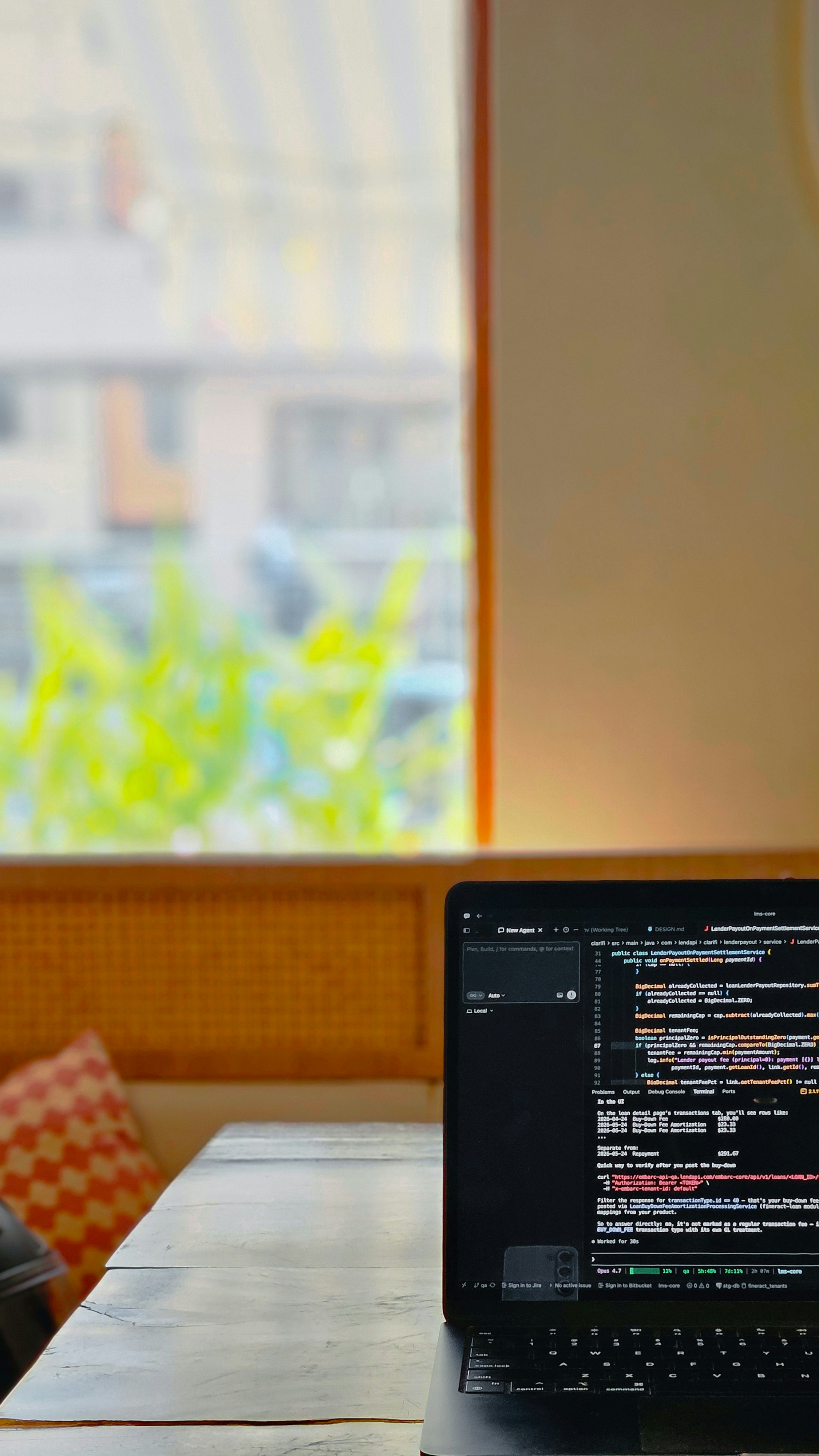 Laptop menampilkan kode di atas meja kayu di dekat jendela.