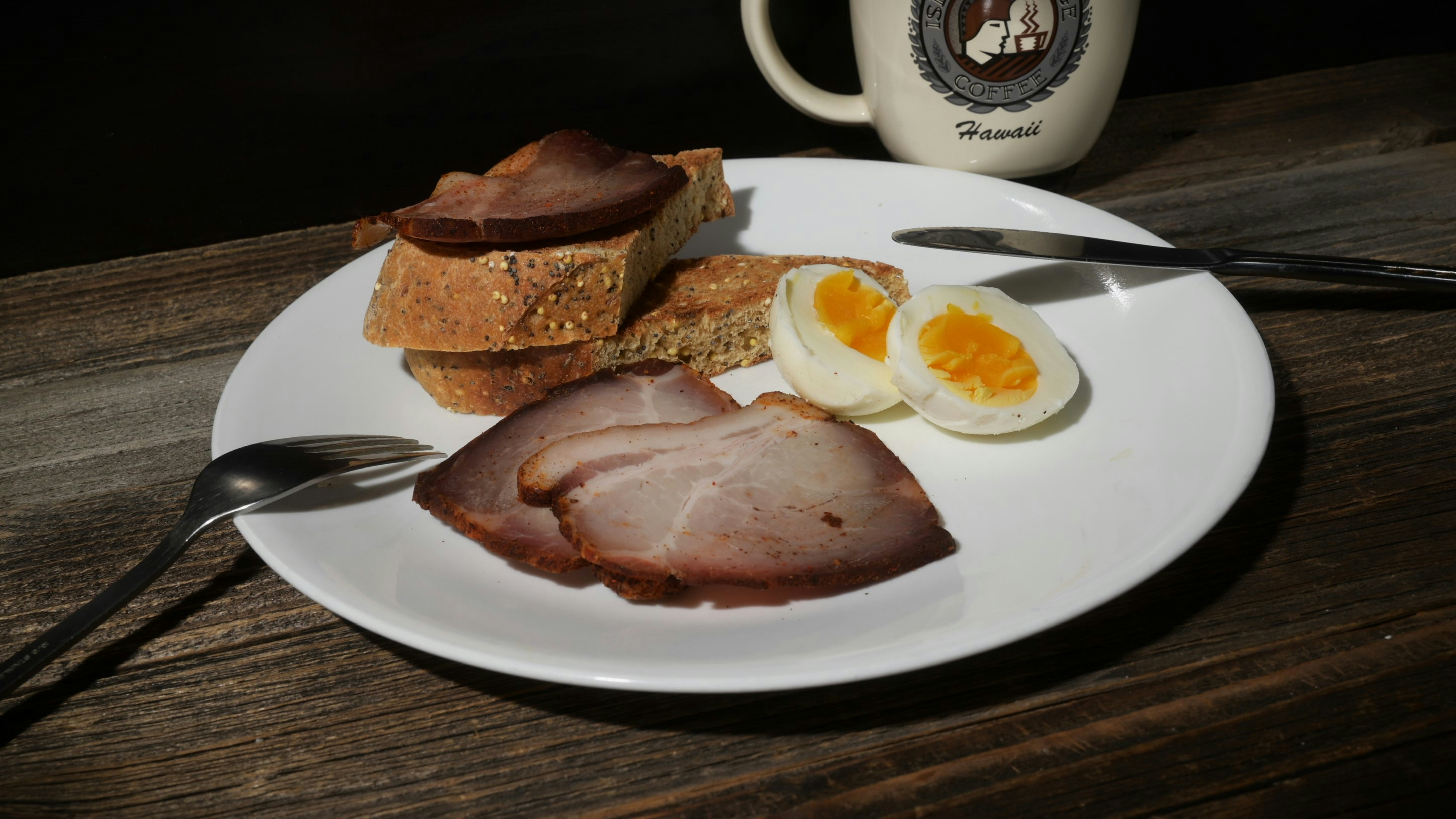 Jambon tranché, pain et œufs durs dans une assiette.