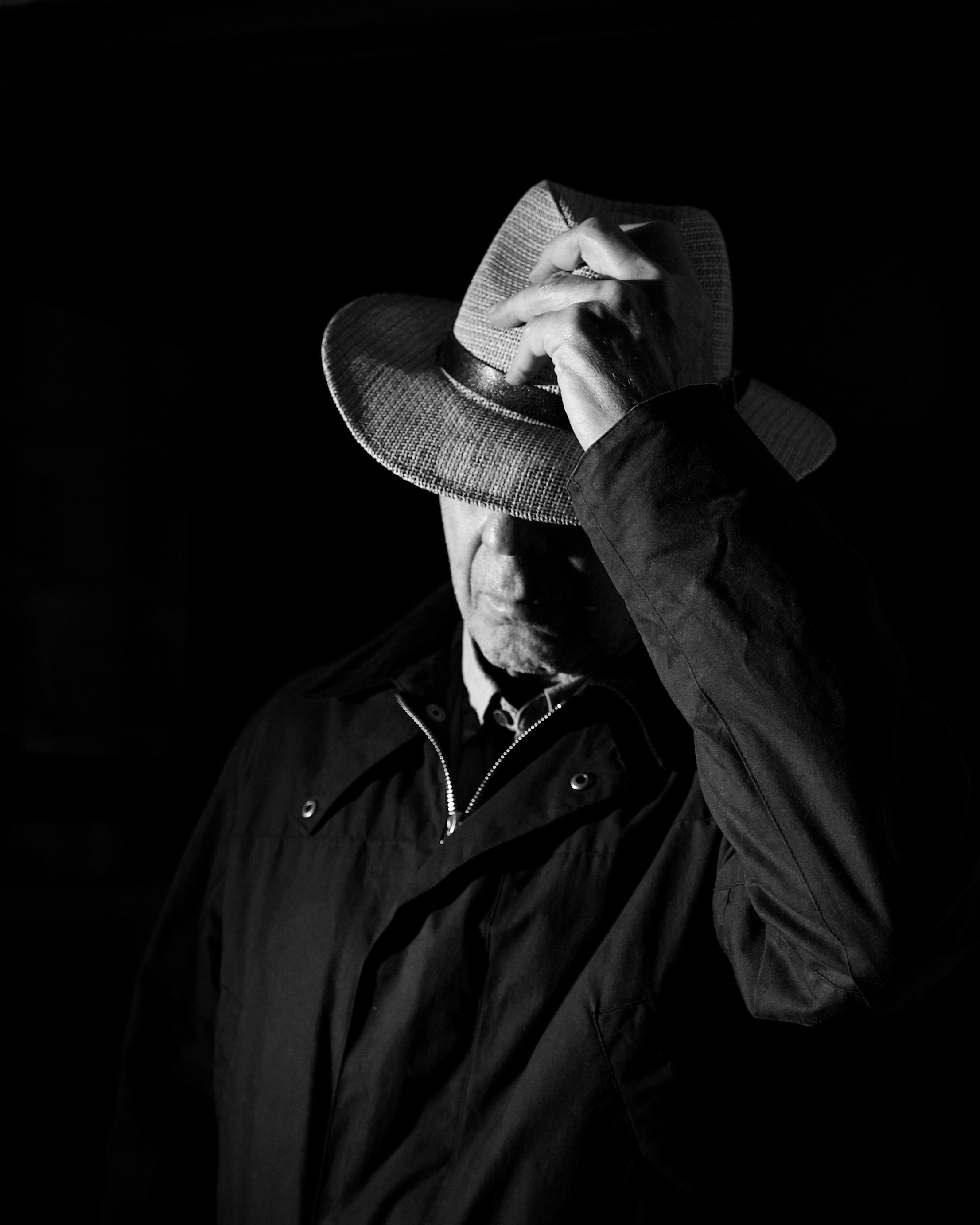 Man in hat tipping it forward in darkness