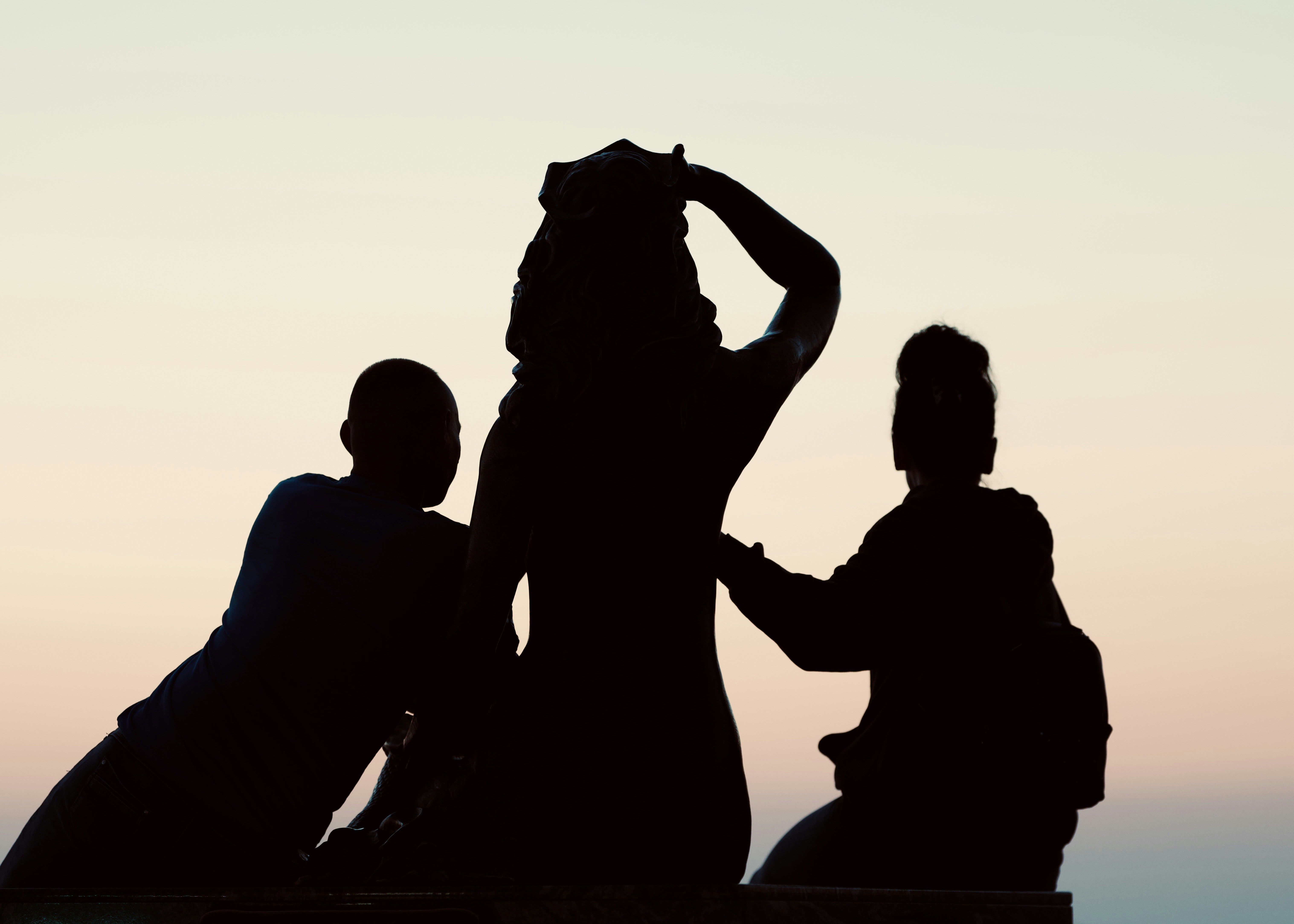Silhouettes of three people against a sunset sky