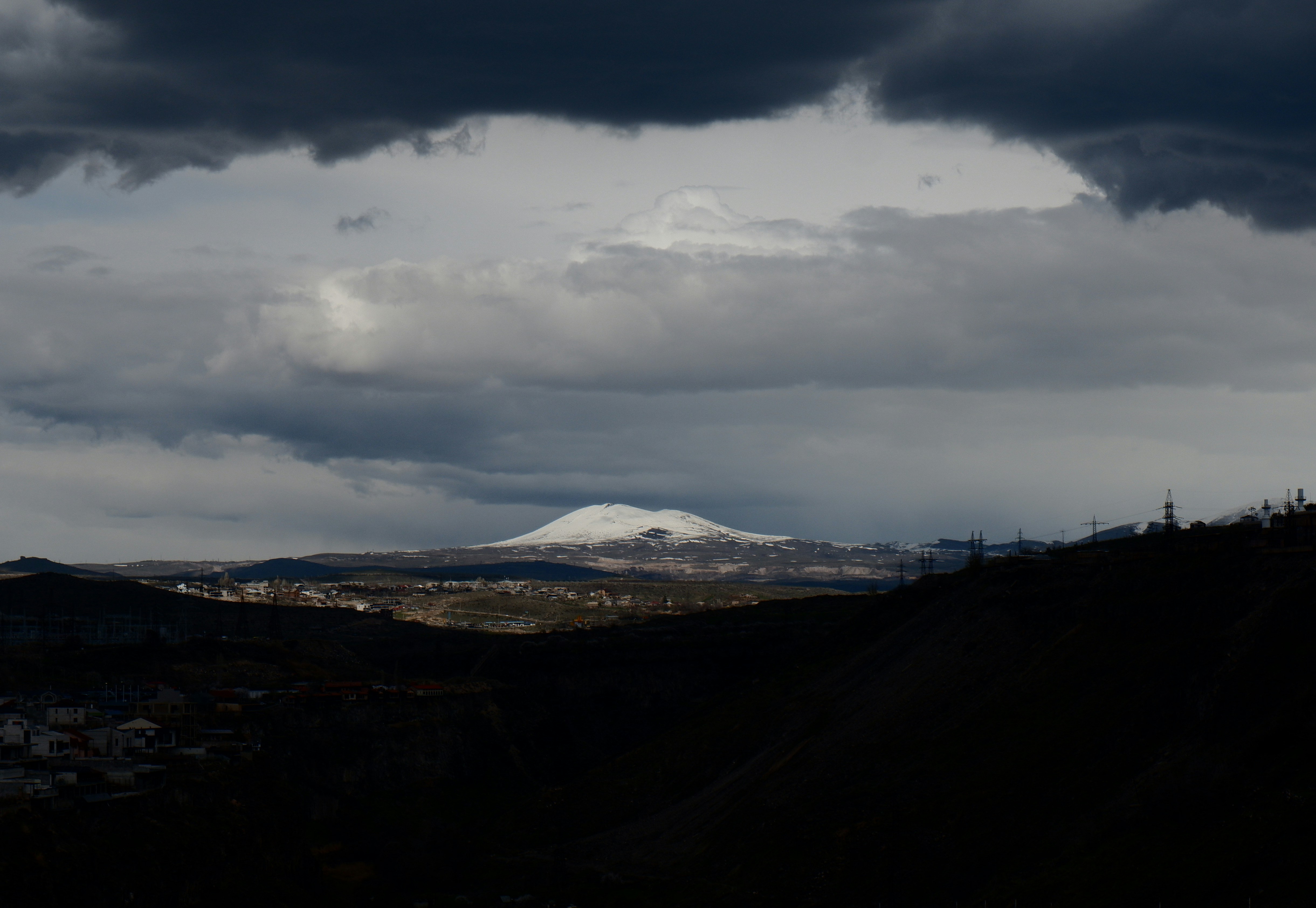 Snow-capped mountain under dramatic stormy clouds