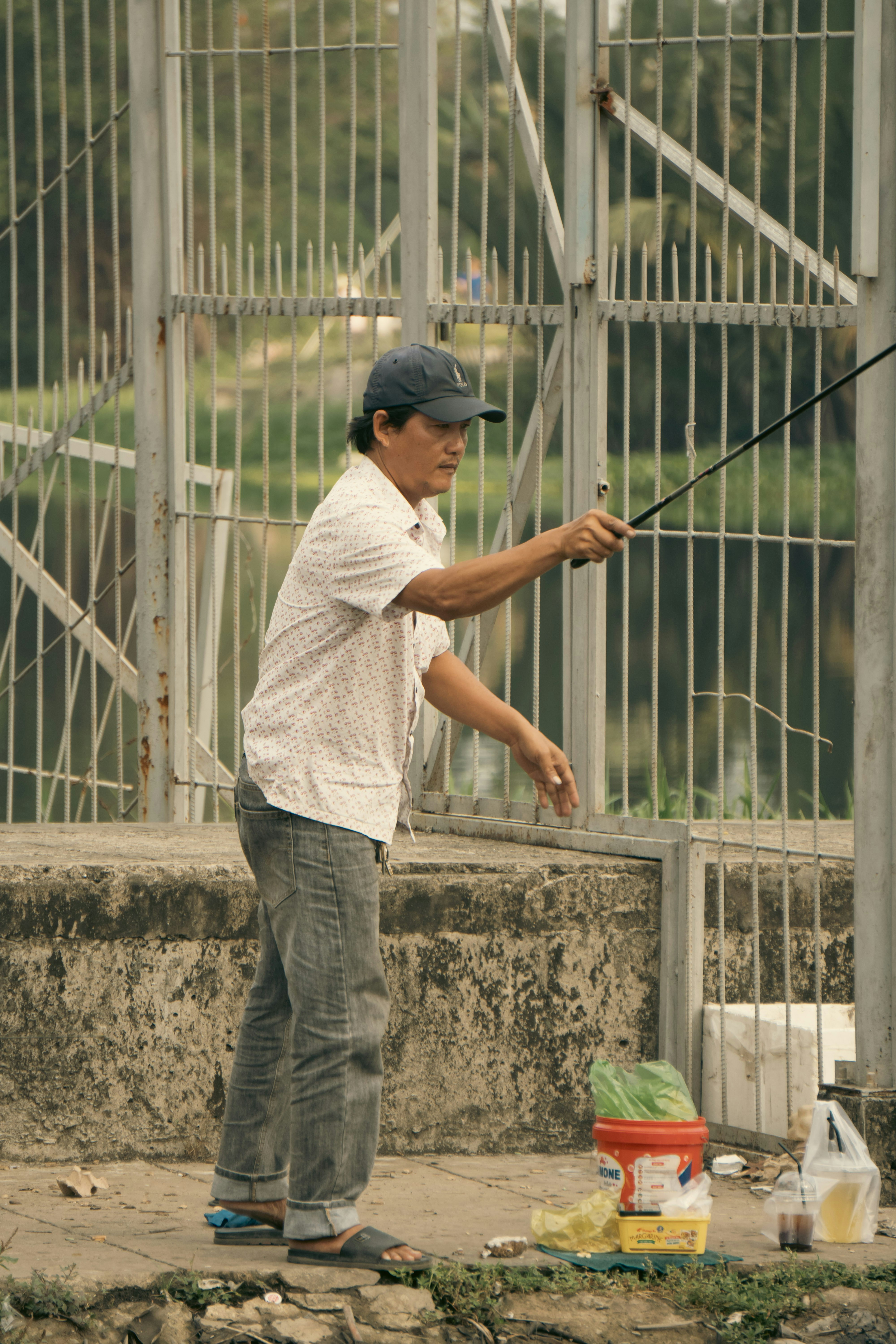 Pria memancing di tepi pagar logam dengan ember