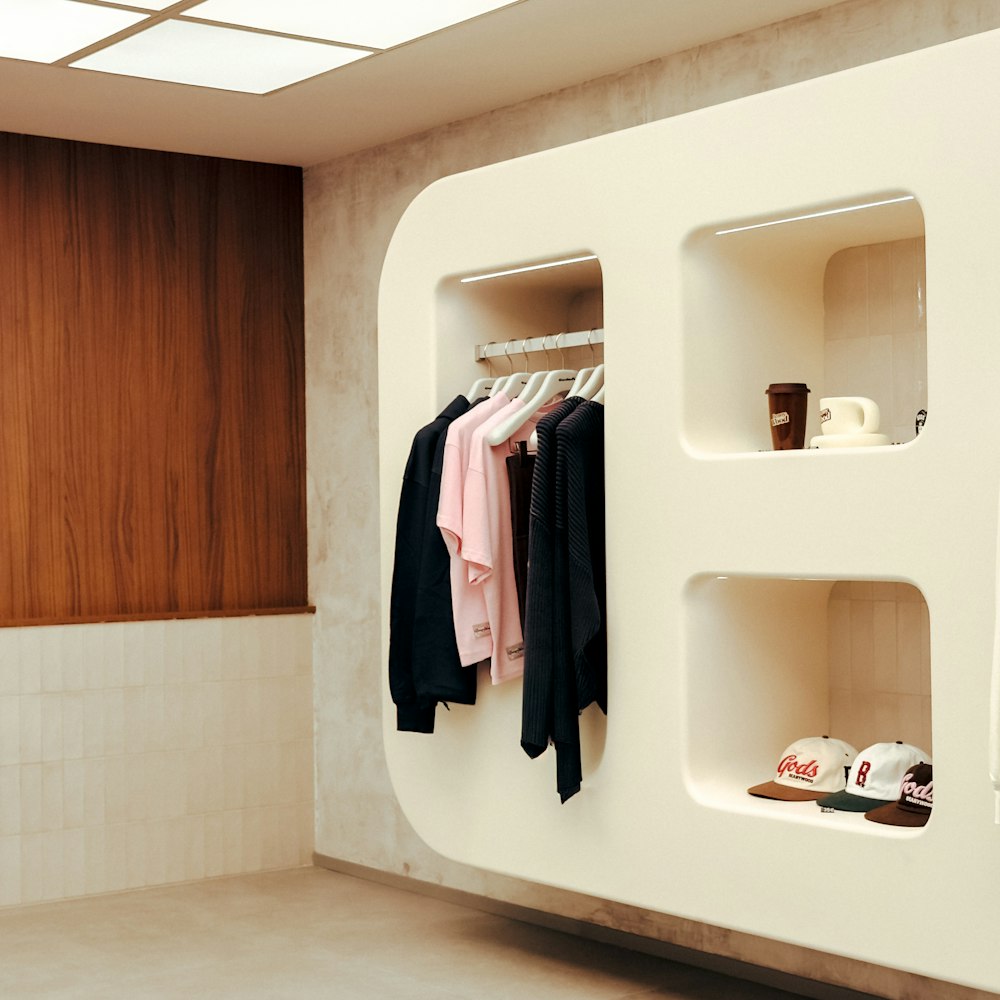 Minimal retail display wall with integrated shelving and a garment rail