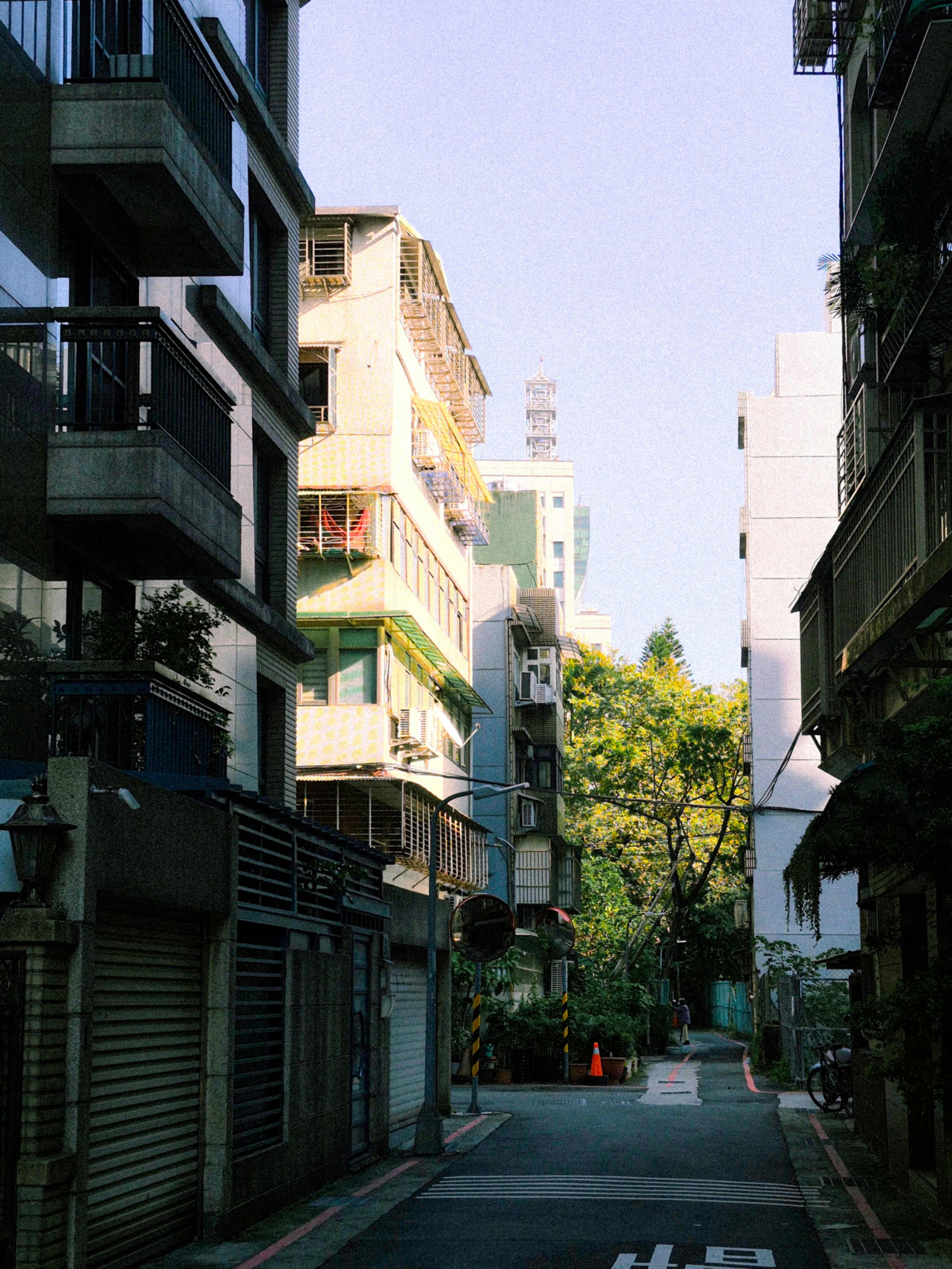 Narrow street between apartment buildings with trees.