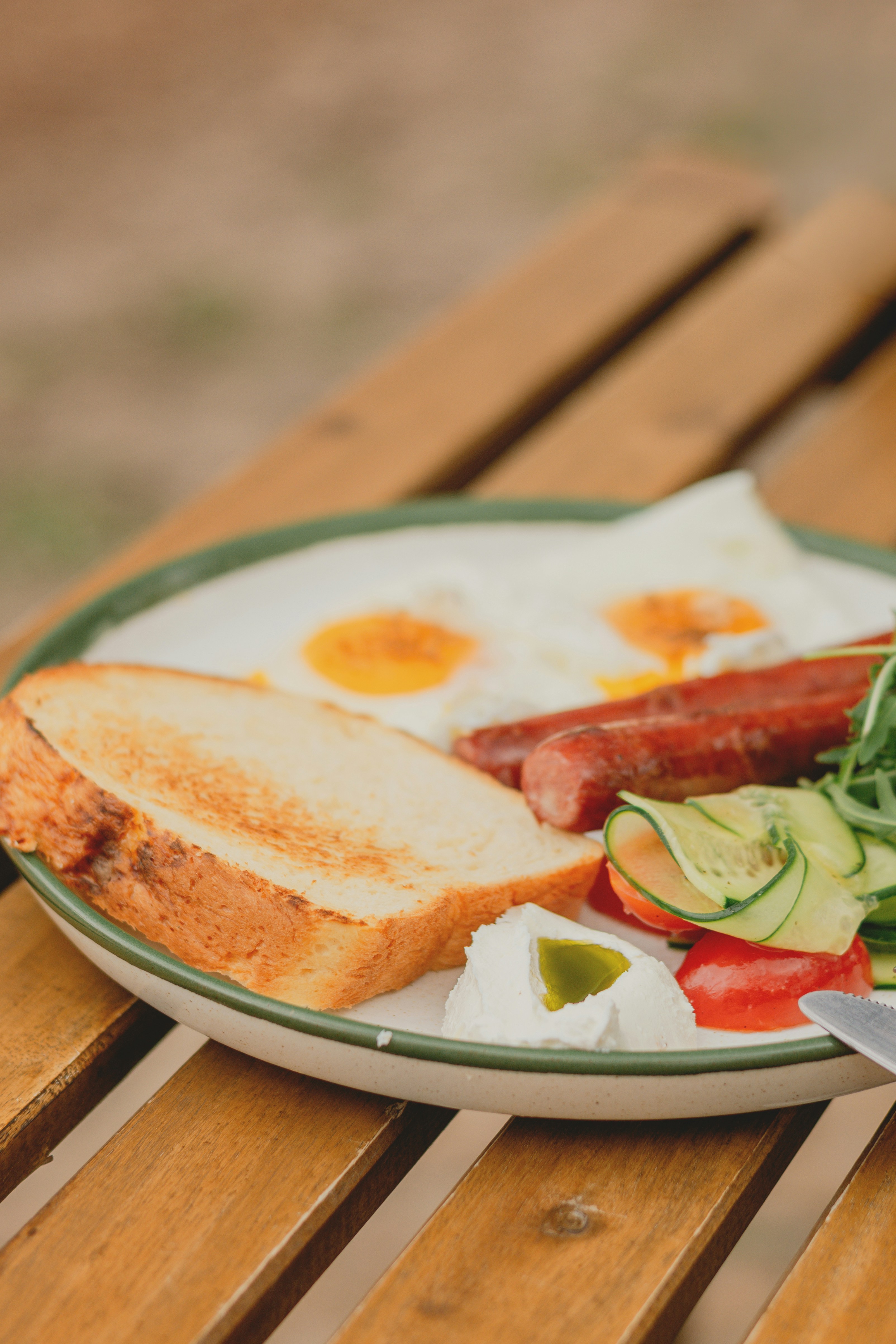 Fried eggs, sausage, toast, and salad on a plate.