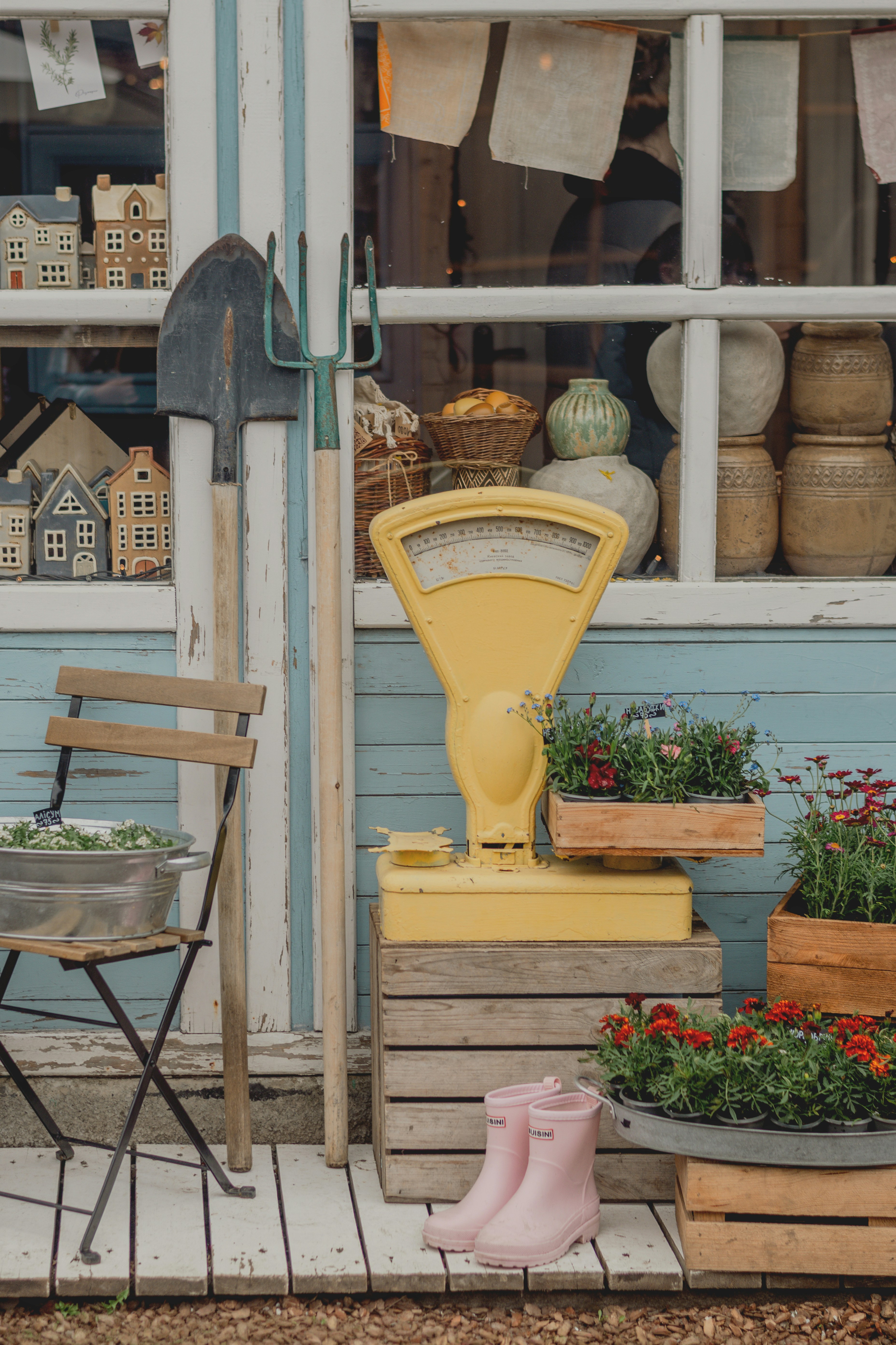 Garden tools, yellow scale, and flowers outside building