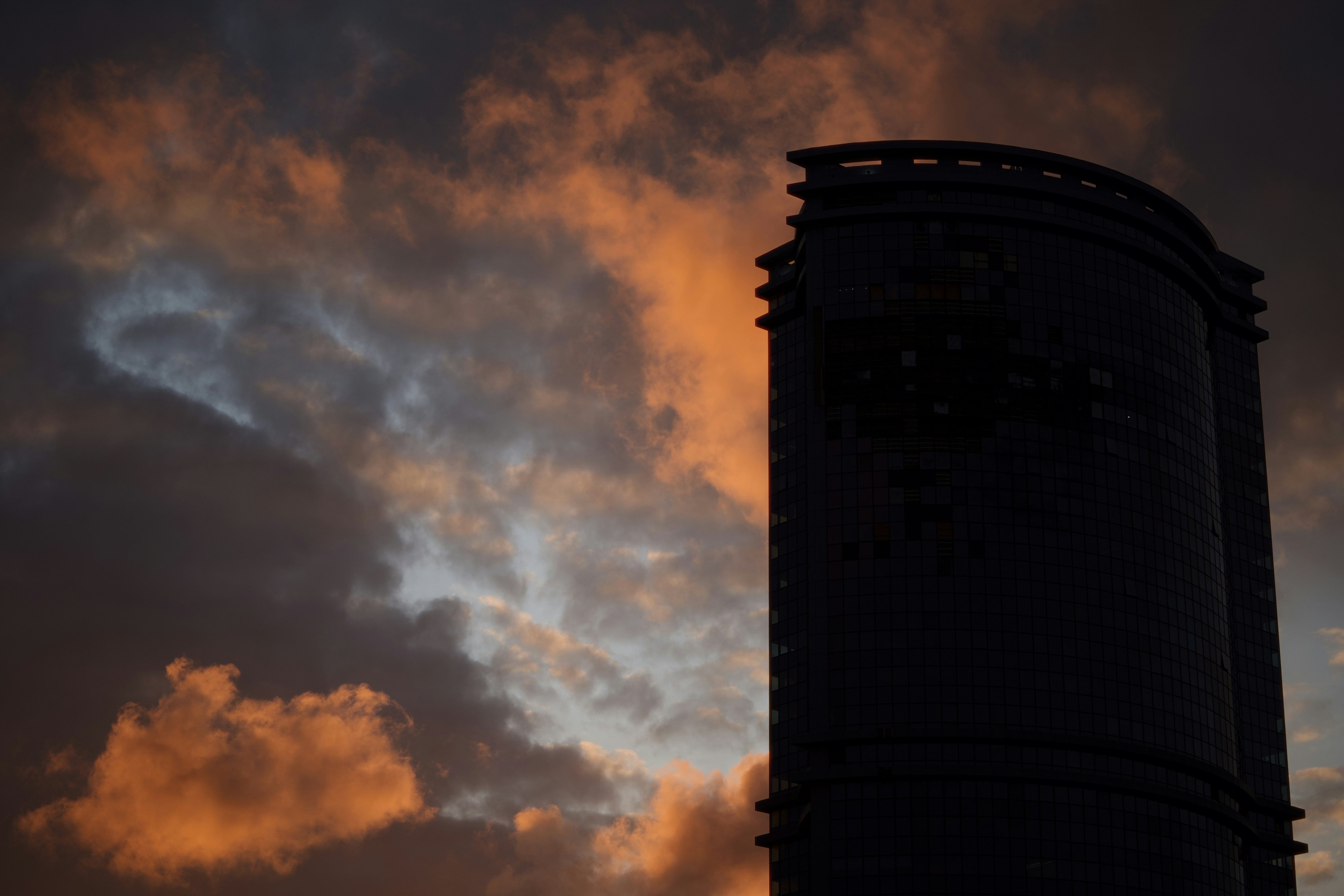 Silhouette of a tall building against a dramatic sunset sky.