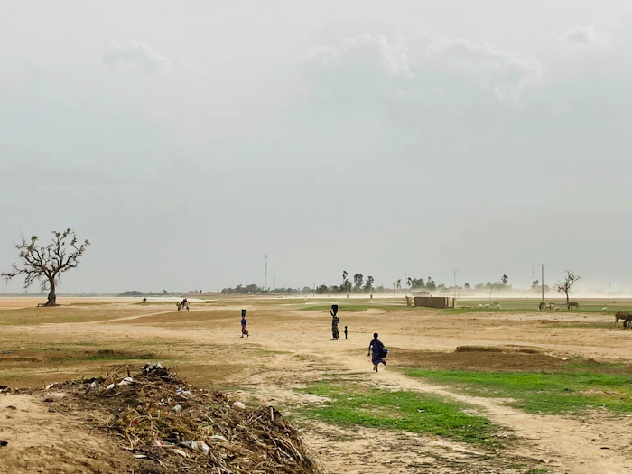 People walking along a dry Sahel landscape path in Mali