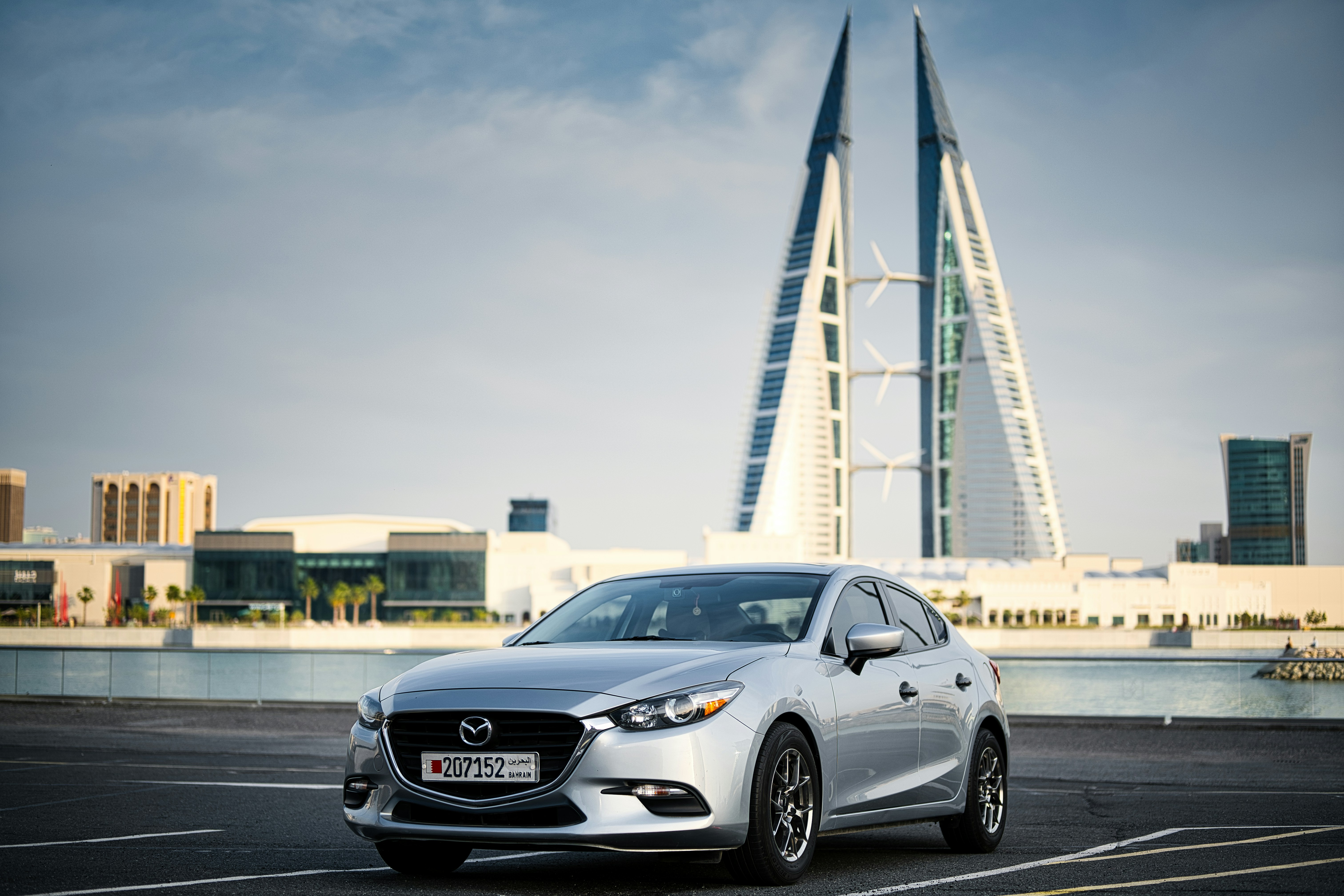 Silver mazda parked with modern buildings in background