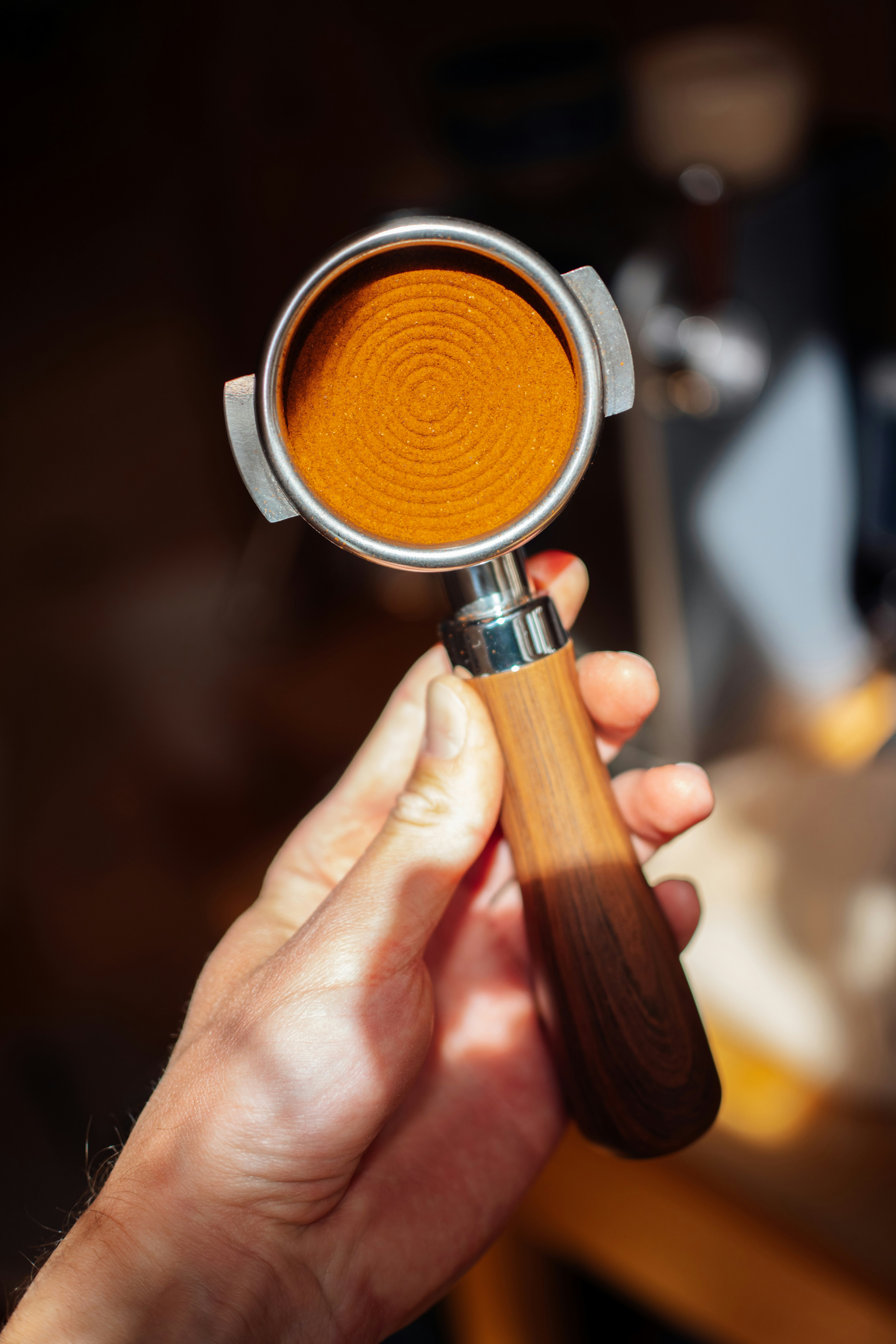 Hand holding espresso portafilter with ground coffee