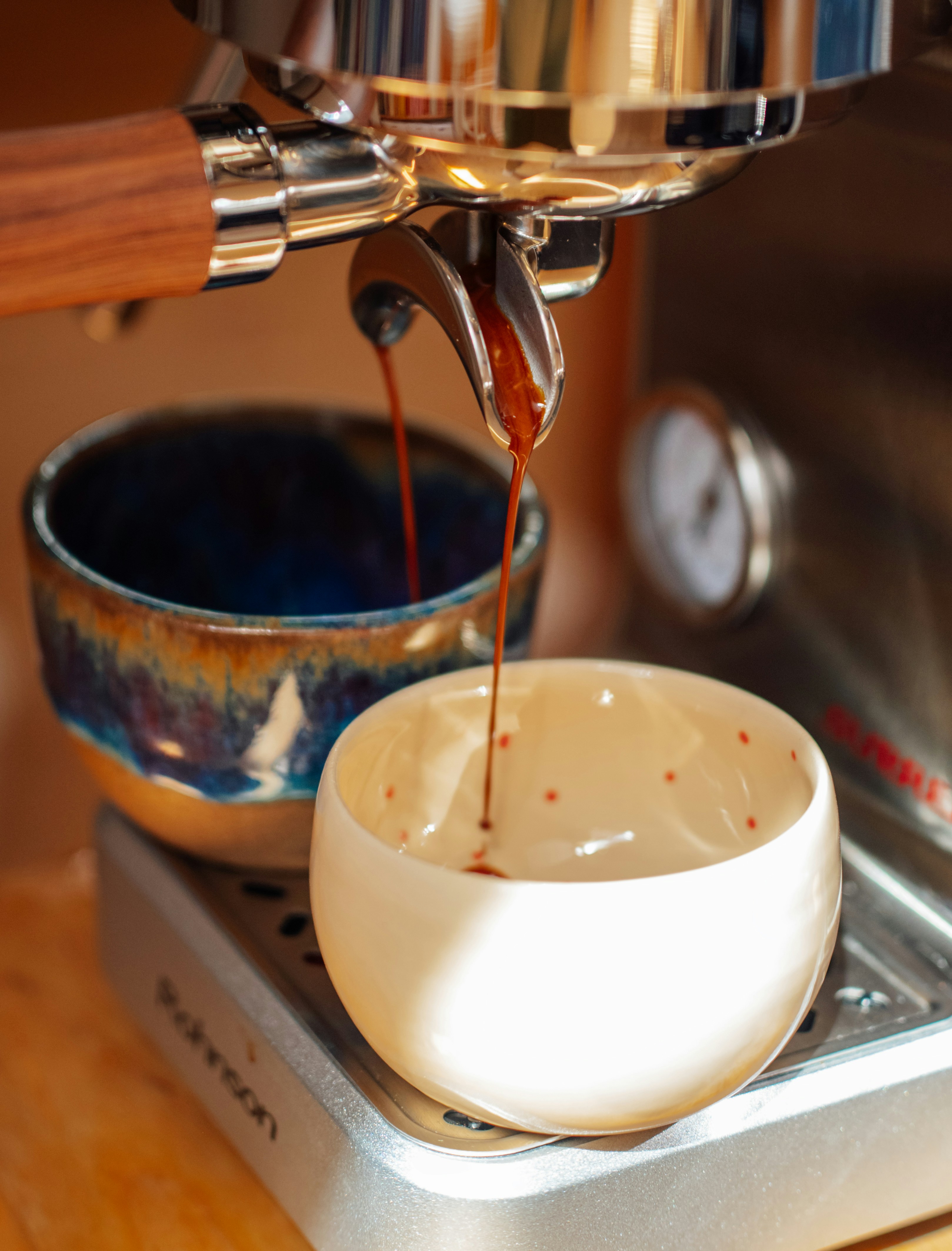 Espresso pouring into a small cup from machine.