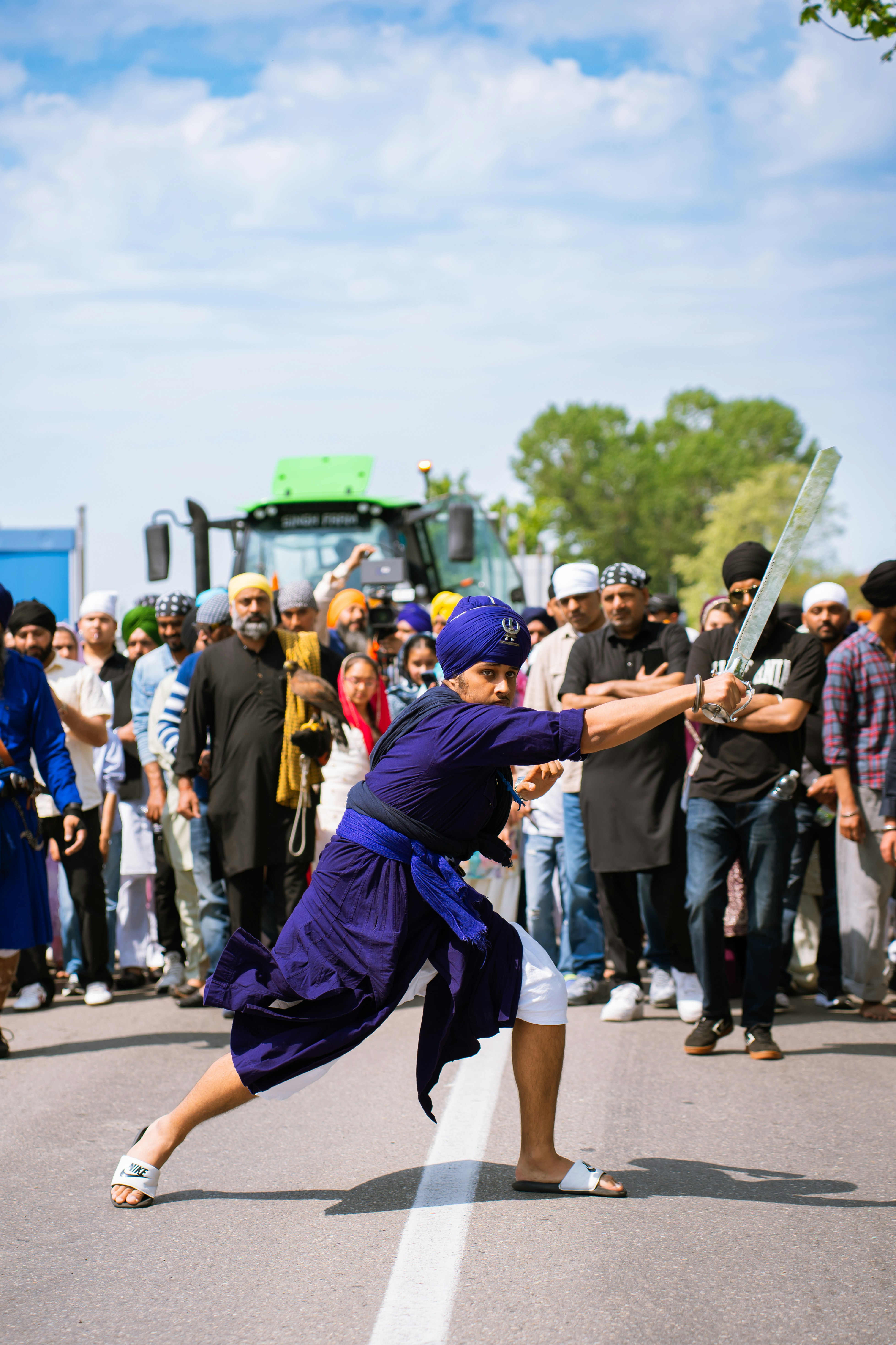 Man in blue uniform wields sword at outdoor gathering