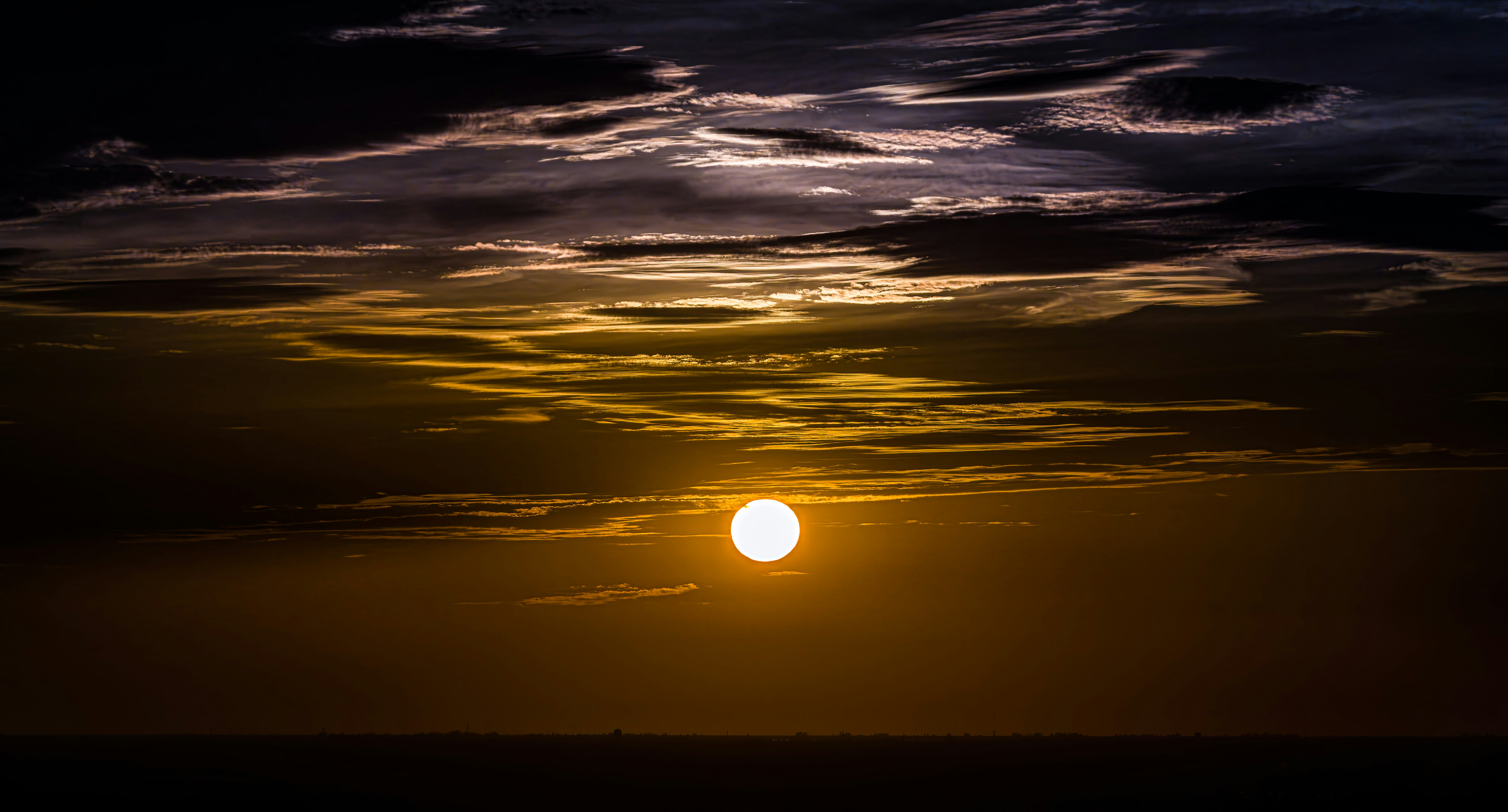 Le soleil se couchant derrière des nuages dramatiques au-dessus de l’océan
