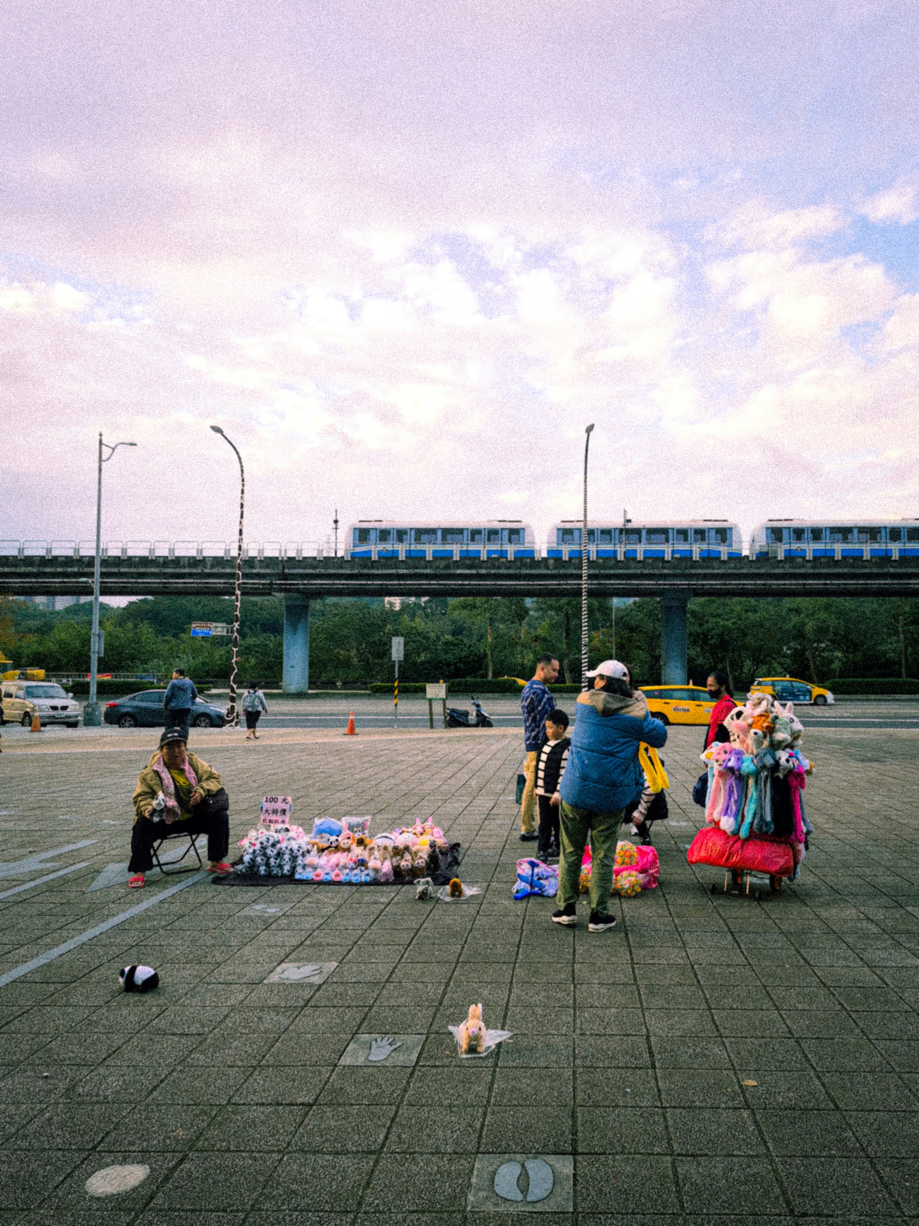 Street vendors selling goods with a train overhead