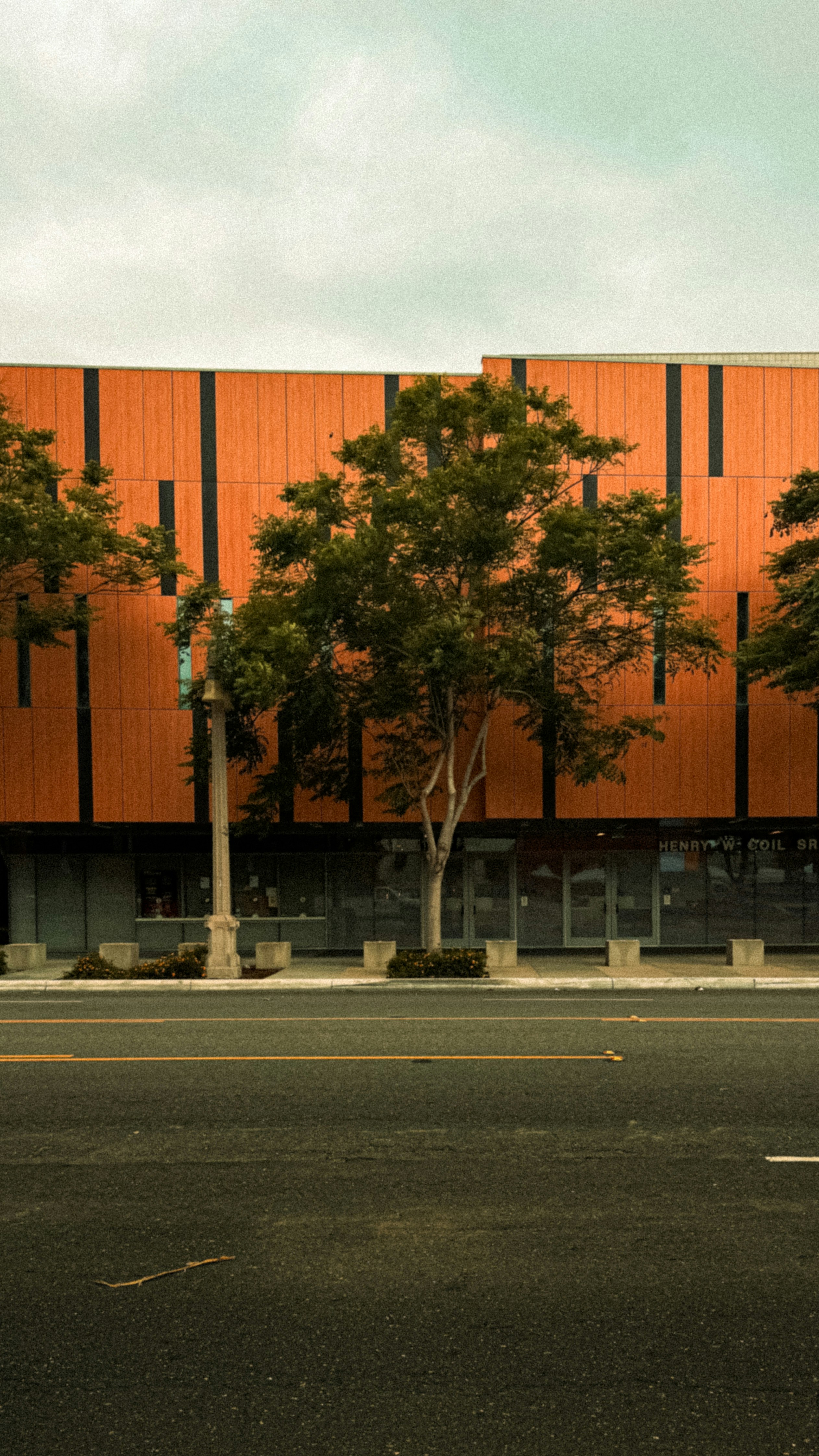 Modern building with orange facade and trees outside