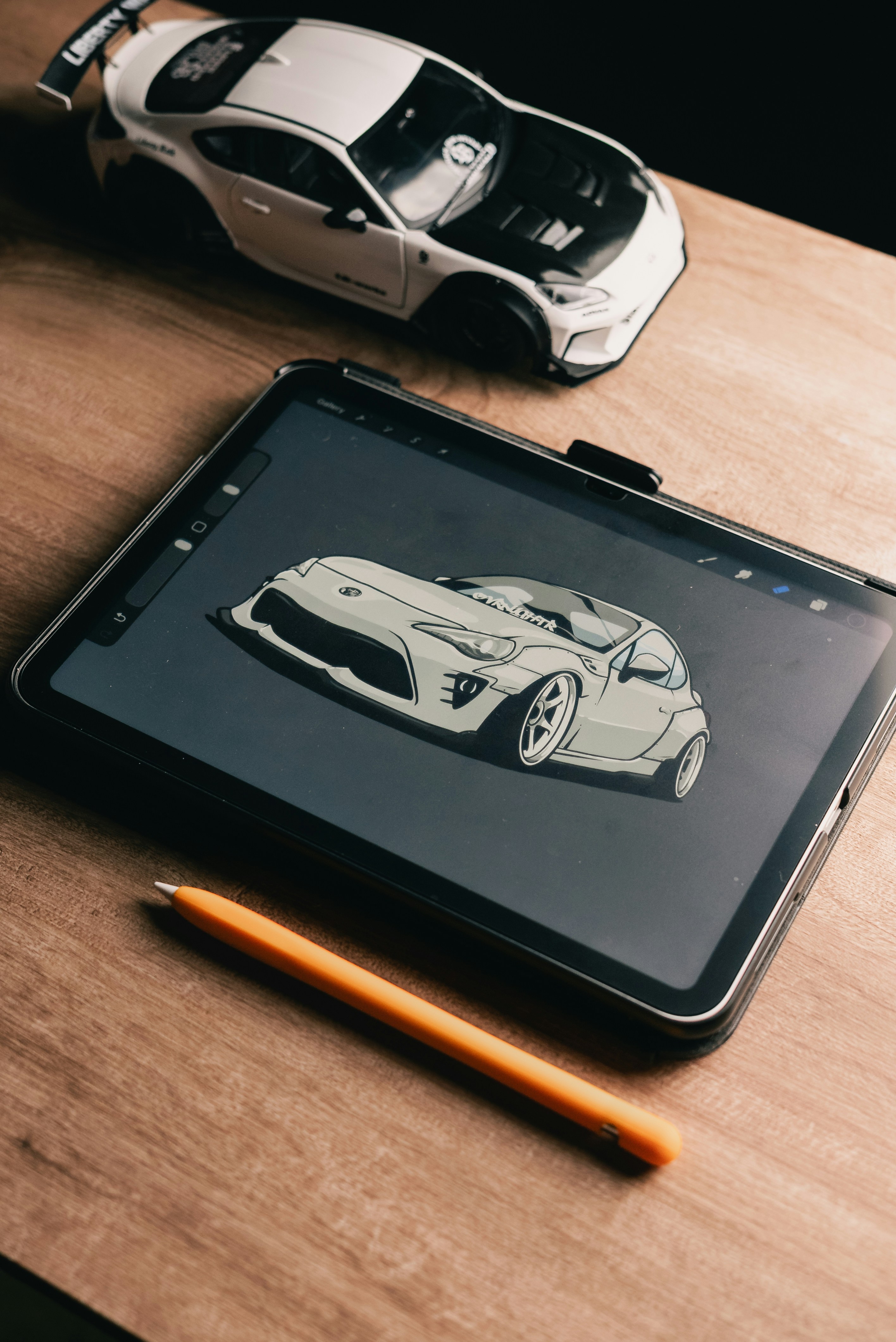 Tablet che mostra un disegno di un'auto accanto a un modello.