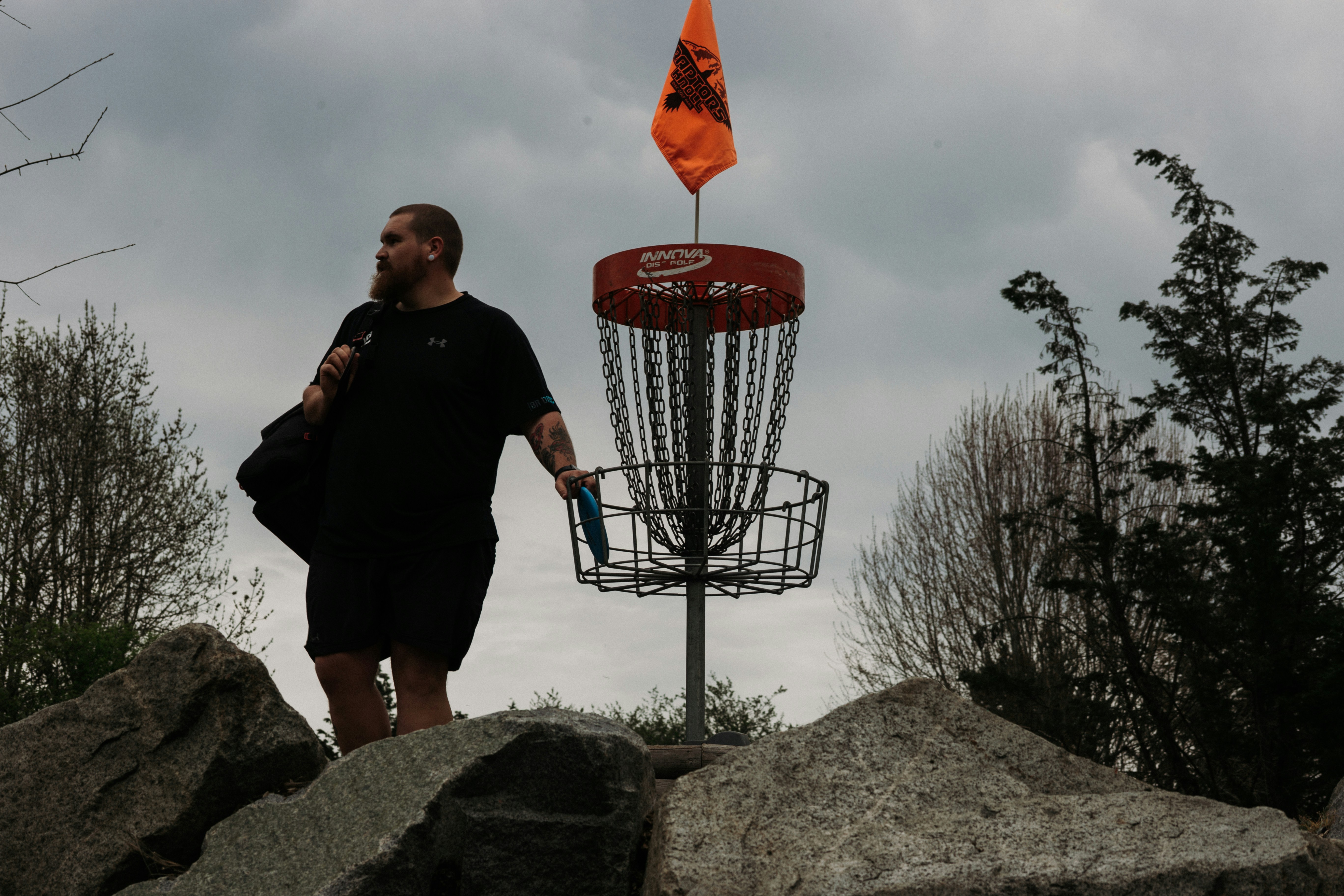 Man walking with disc golf basket and flag