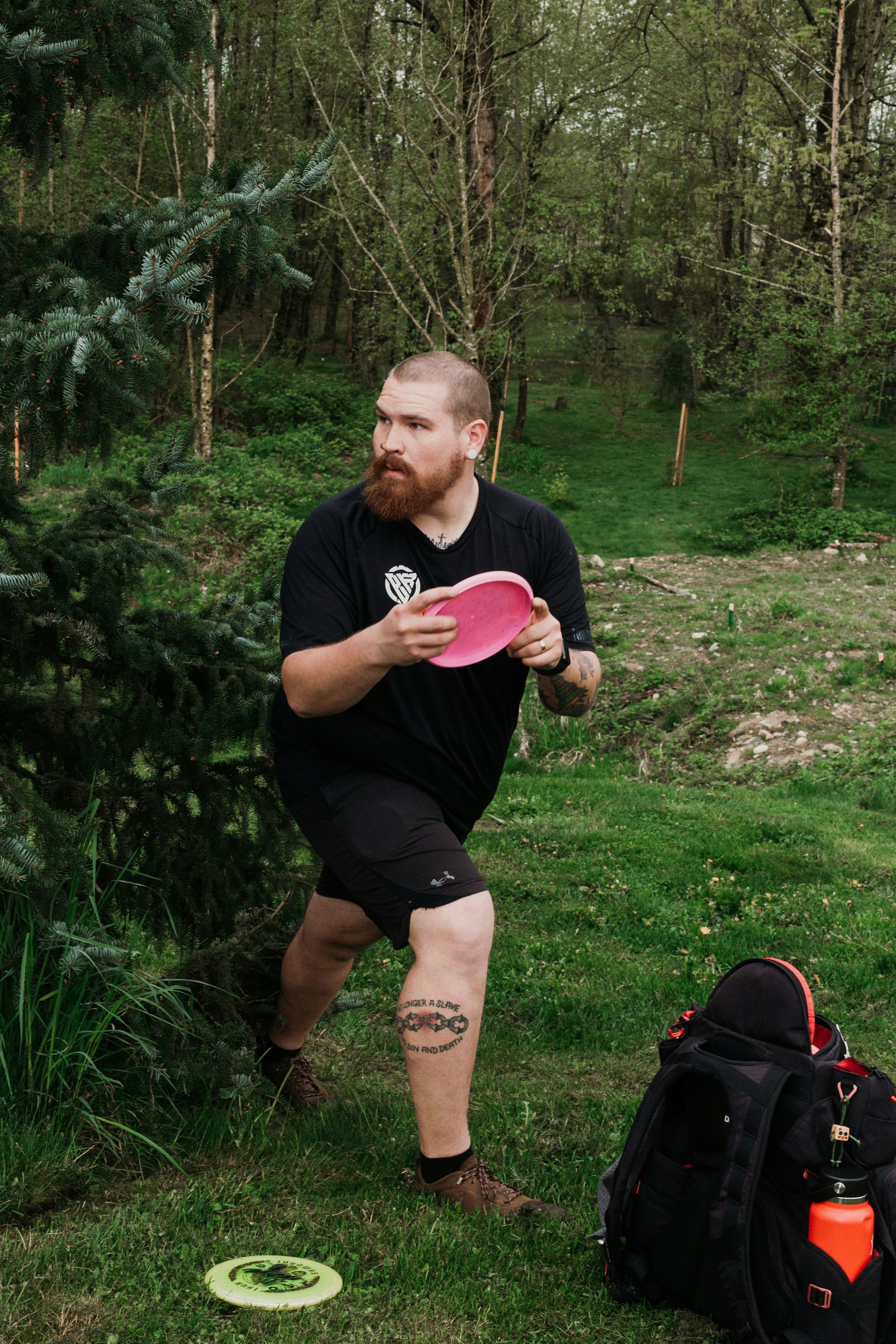 Man throwing a pink disc golf disc in a park.
