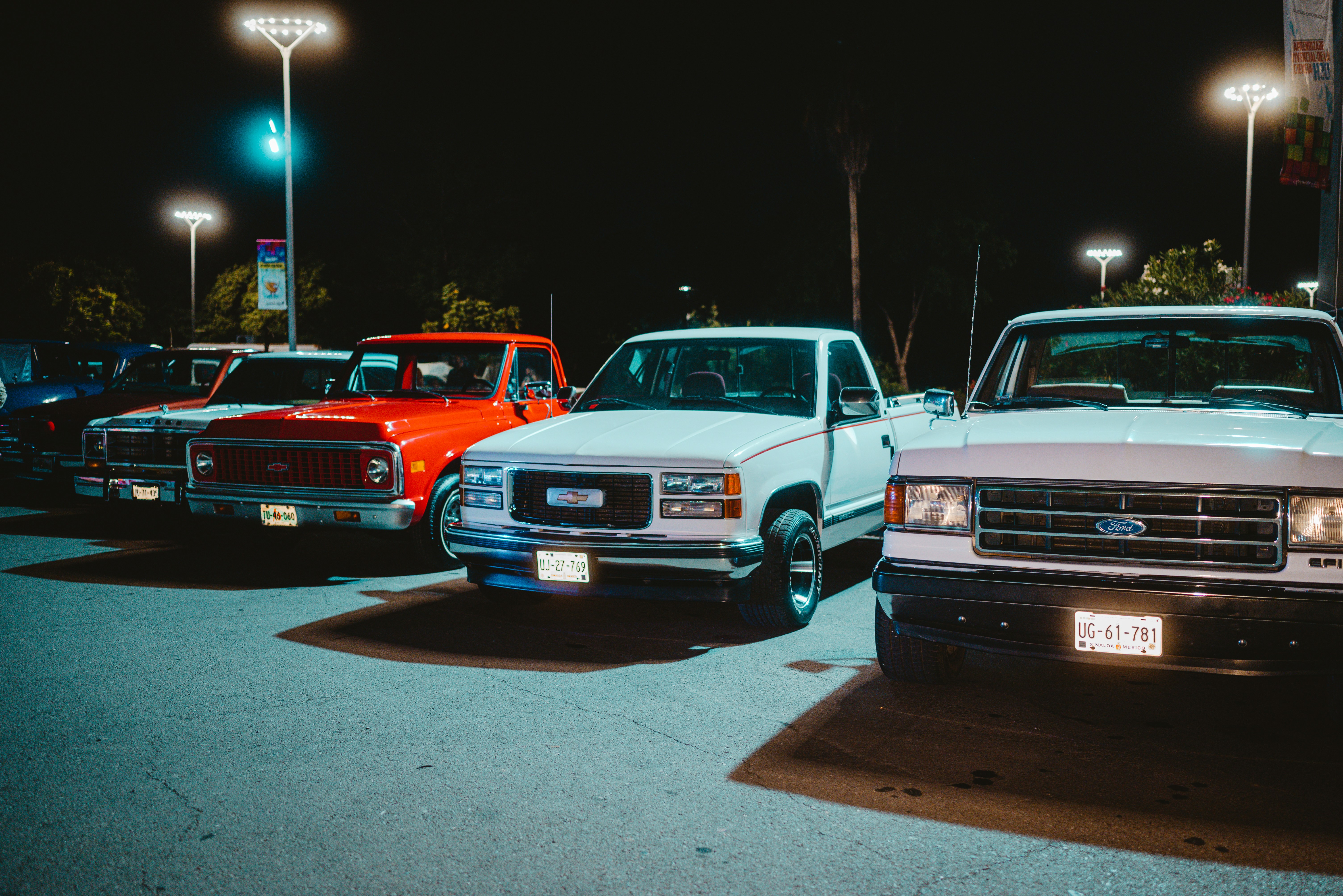 Ford F-150 Lightning GMC Hummer EV trucks - Several pickup trucks parked at night
