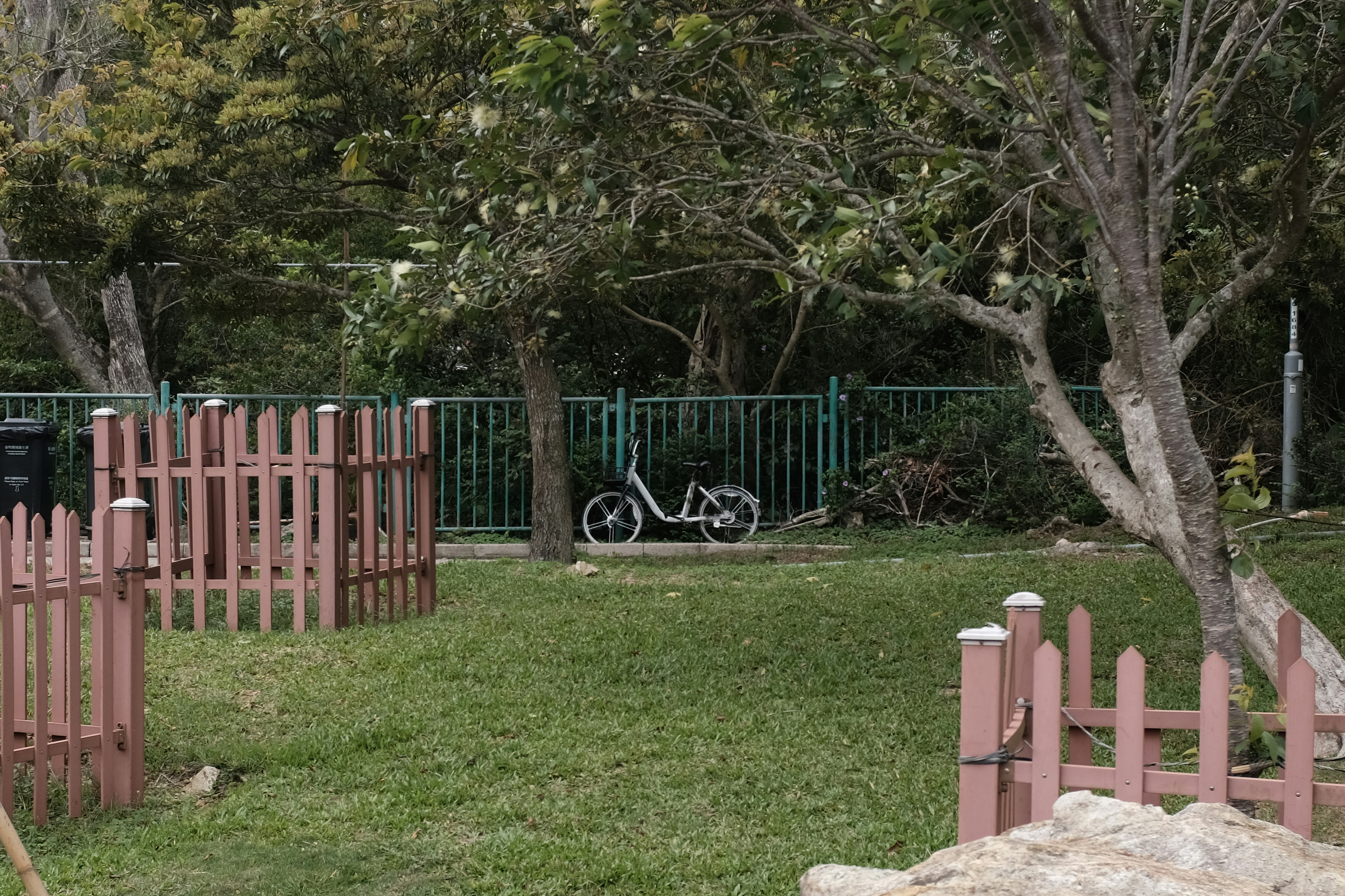 A bicycle parked on a grassy lawn near a fence.