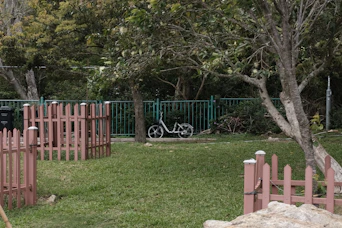 A bicycle parked on a grassy lawn near a fence.
