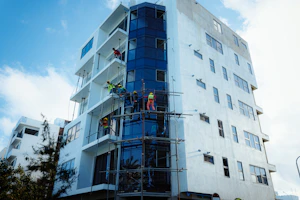 Construction workers on scaffolding installing glass facade.