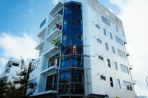 Construction workers on scaffolding installing glass facade.