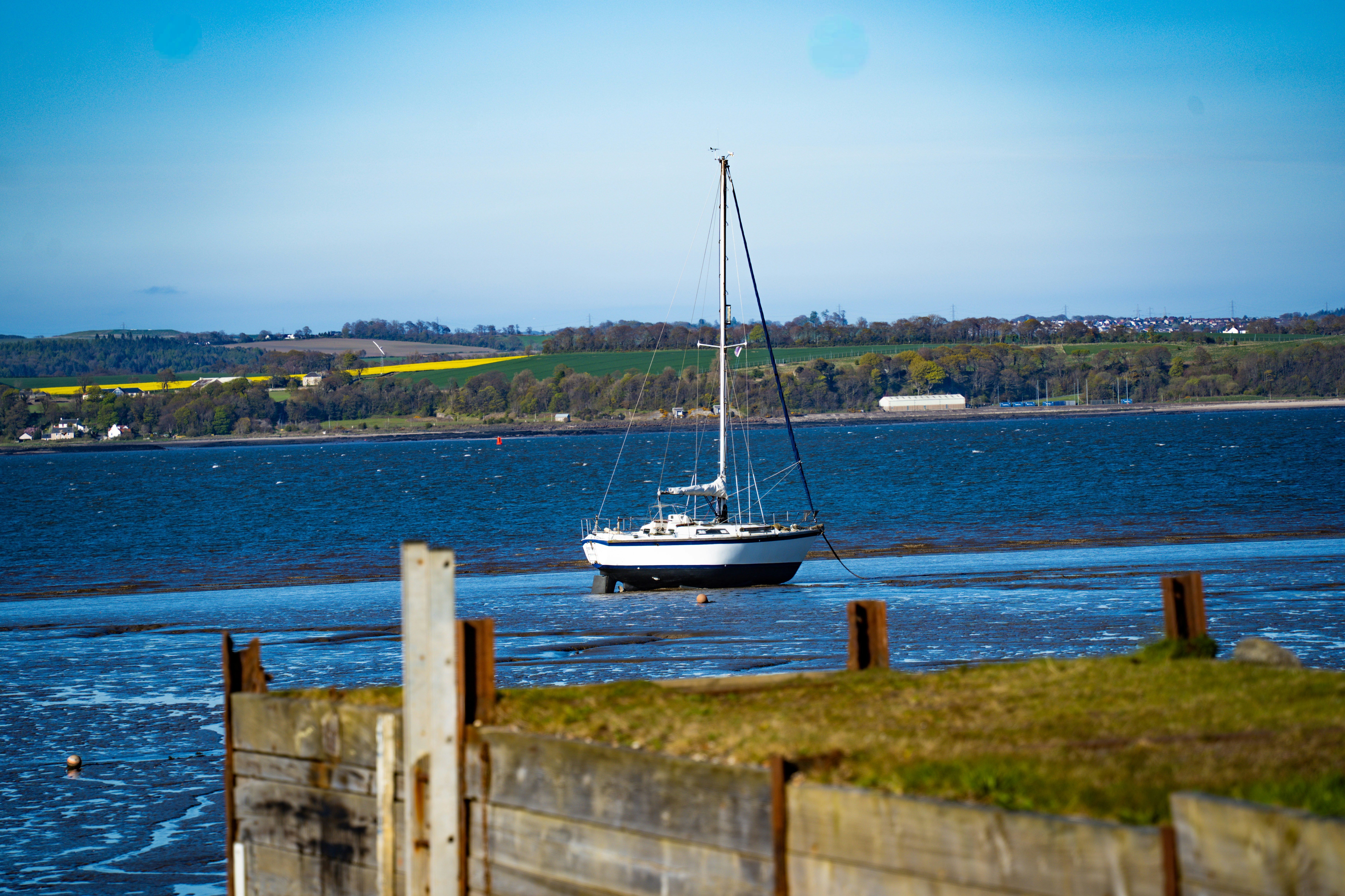A sailboat floats on a calm blue sea.