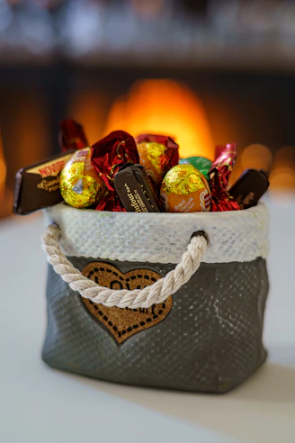 A basket full of assorted chocolates with a fireplace background