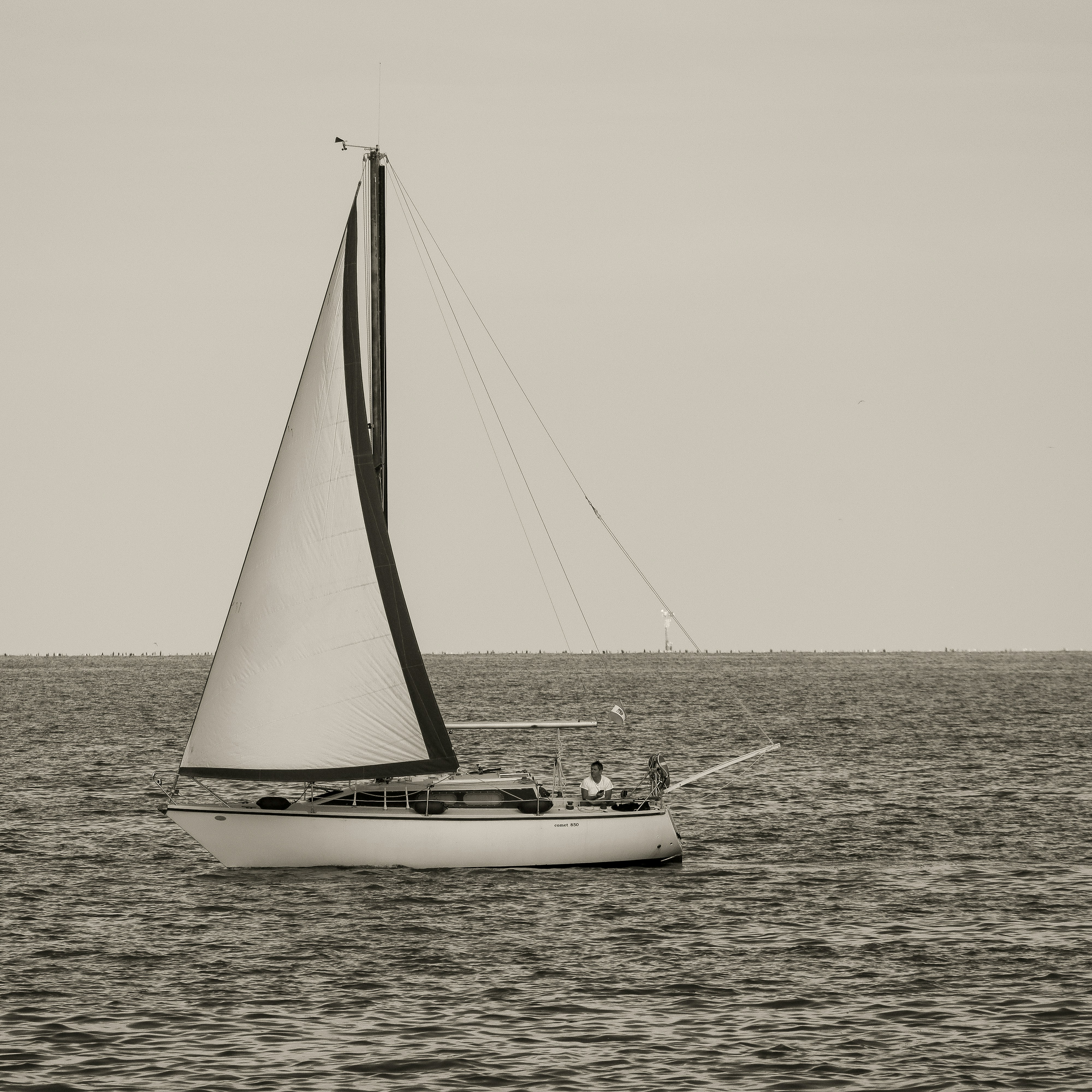 A sailboat glides across the calm sea.