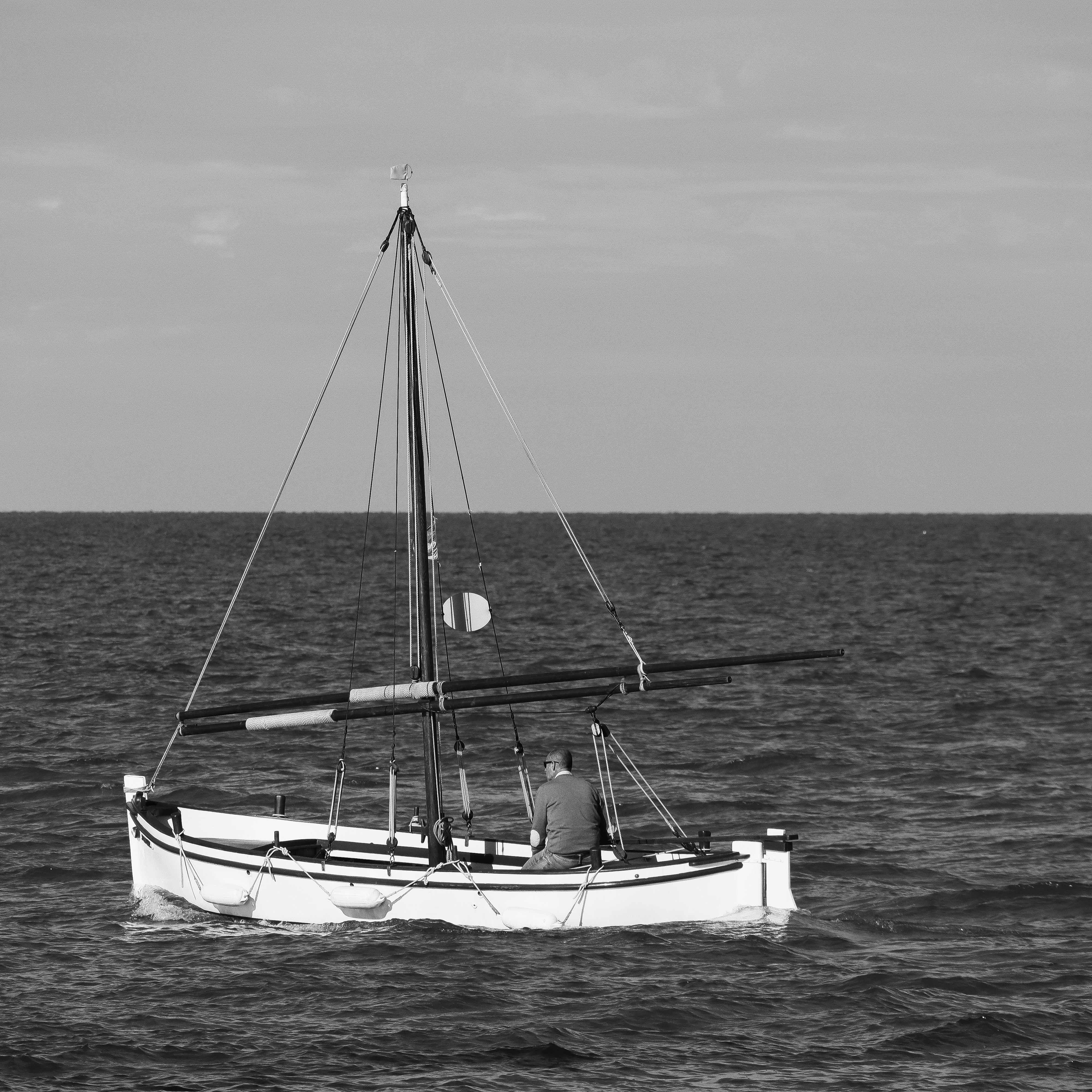 A lone sailboat navigates the open sea.