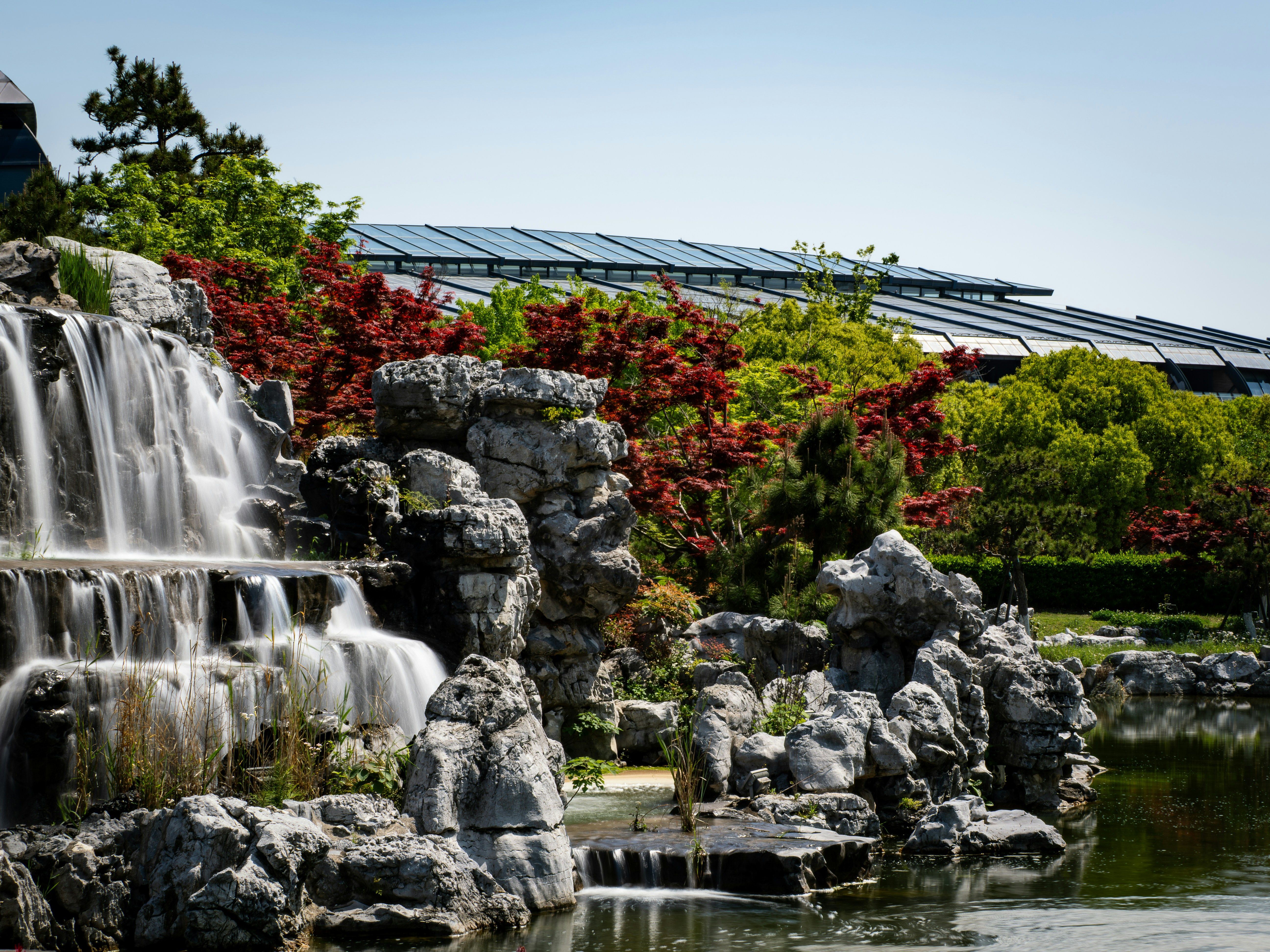 Waterfall cascading over rocks with lush greenery and building