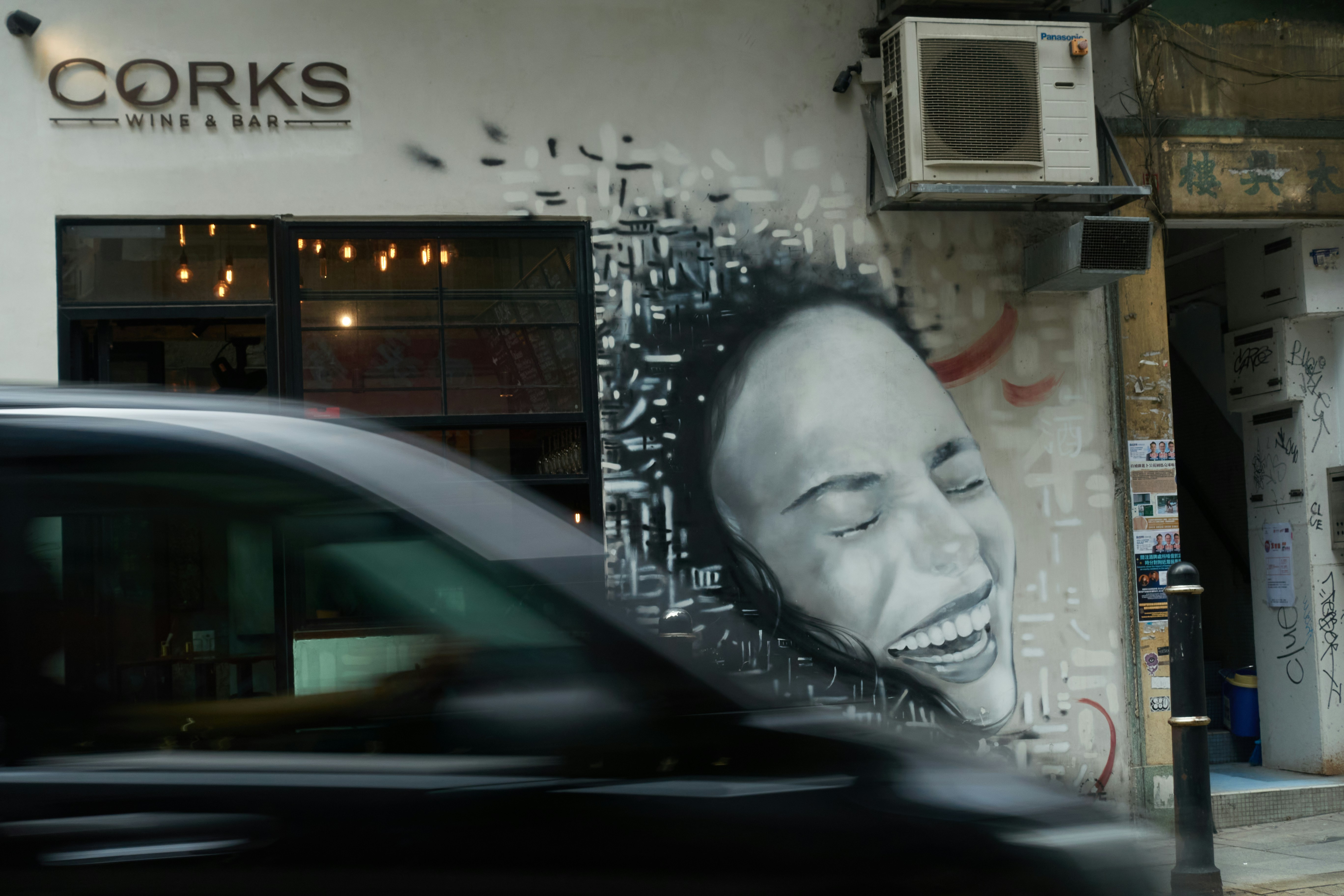 Arte de grafite de uma mulher rindo na parede de um prédio.