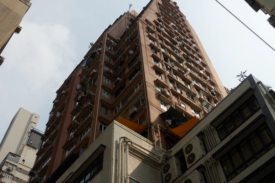 Tall multi-story brick building with numerous windows and balconies in urban setting