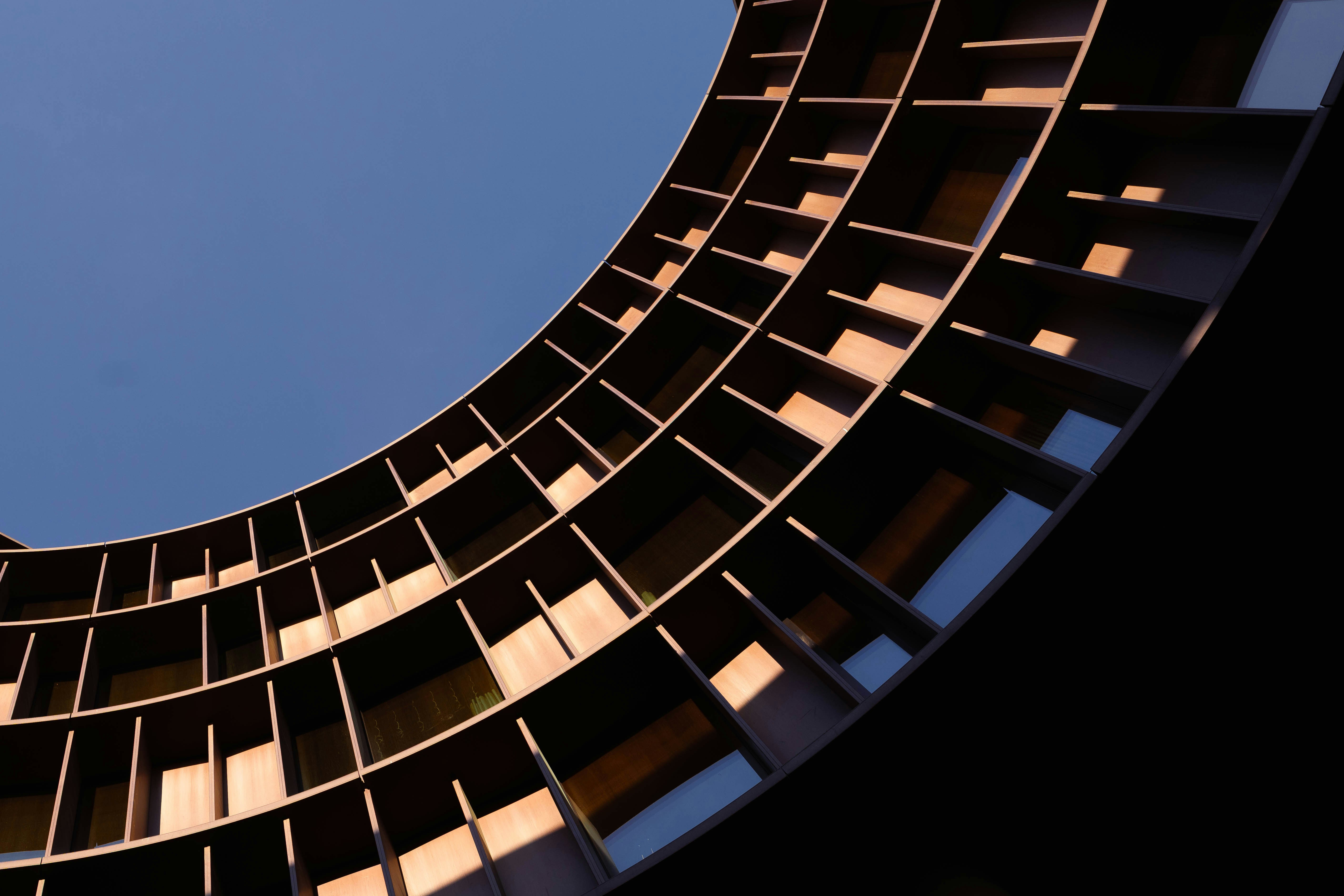 Fachada curva de edificio moderno contra un cielo azul claro