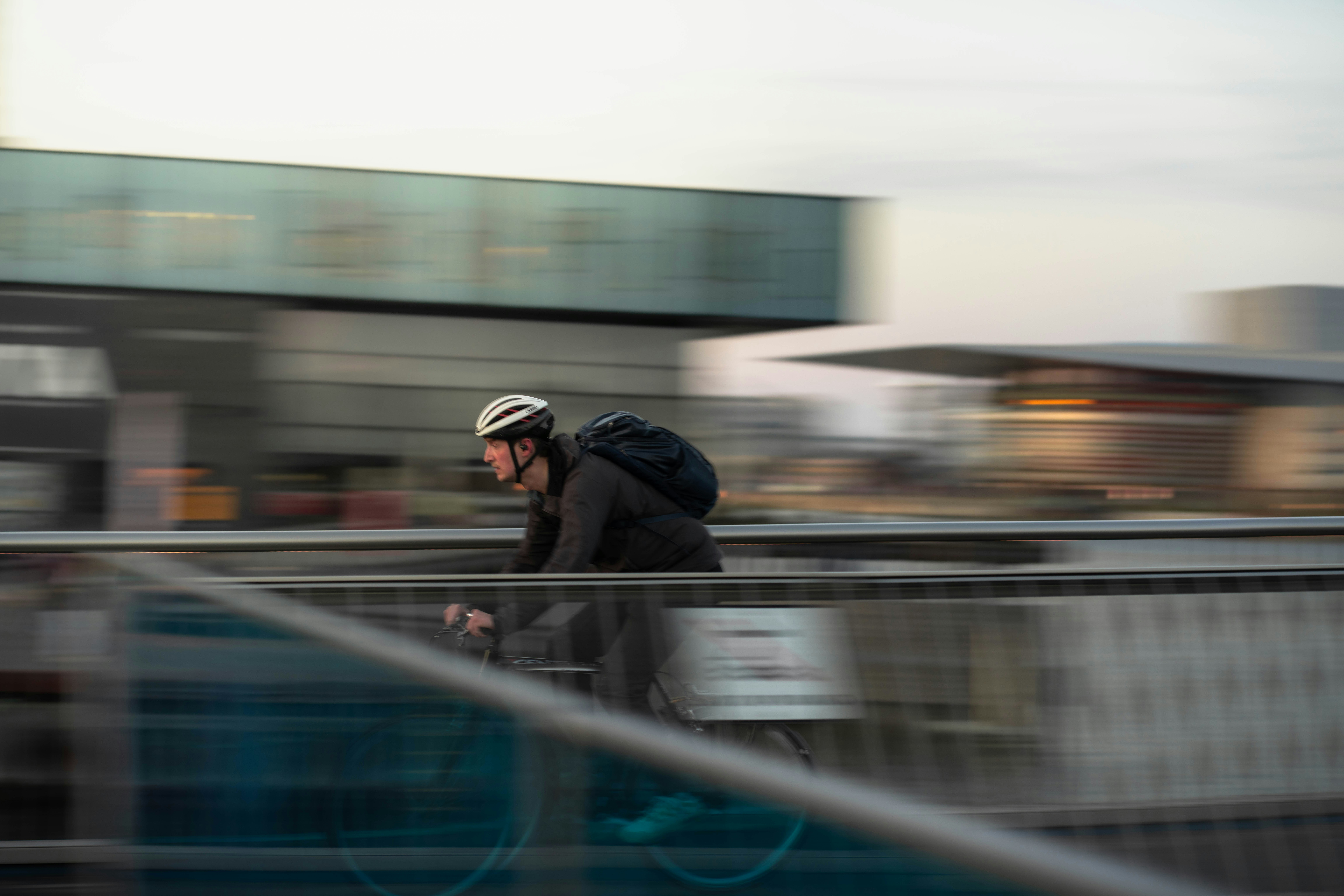 Hombre en bicicleta con mochila en el puente con fondo borroso