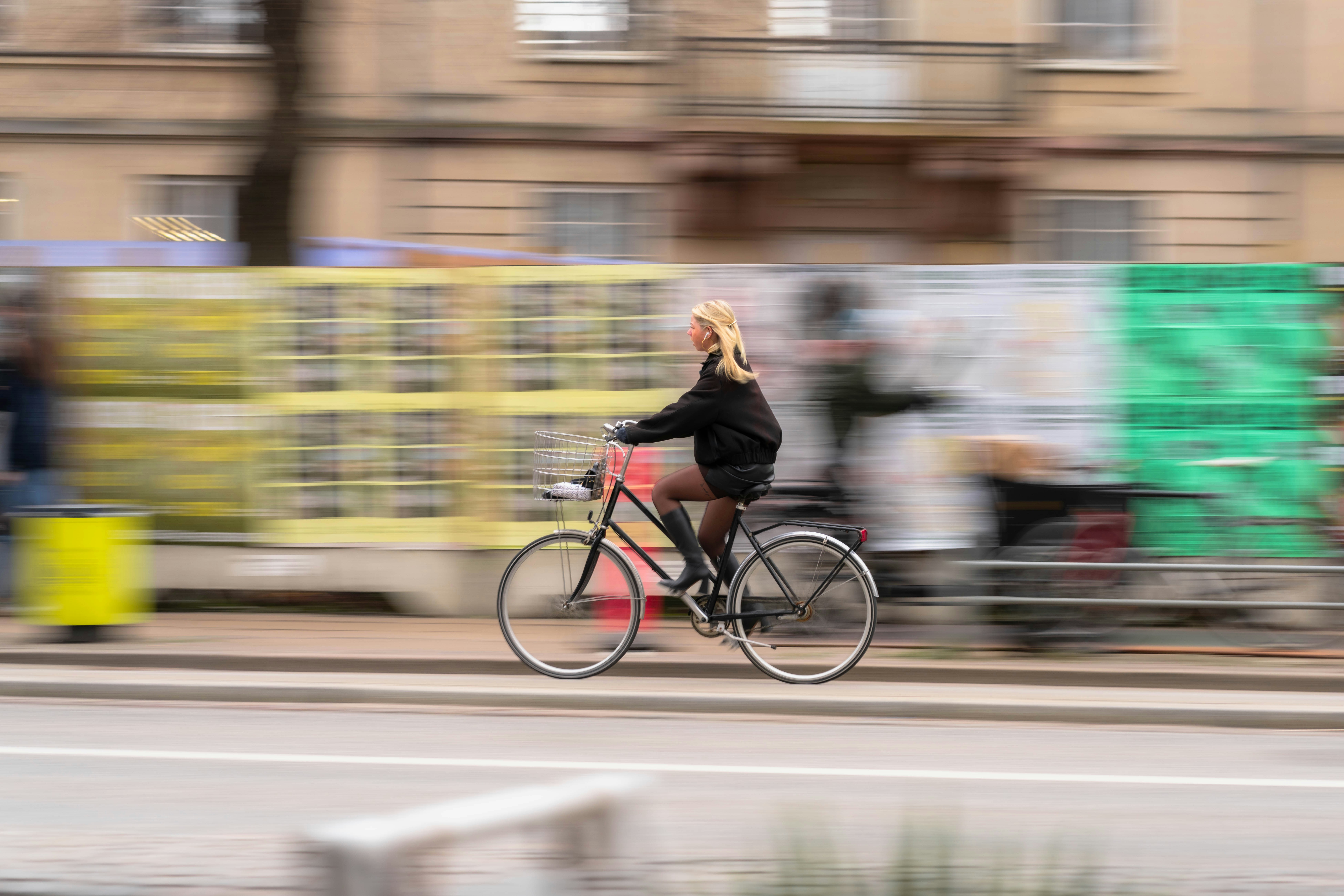 Mujer en bicicleta por una calle con desenfoque de movimiento
