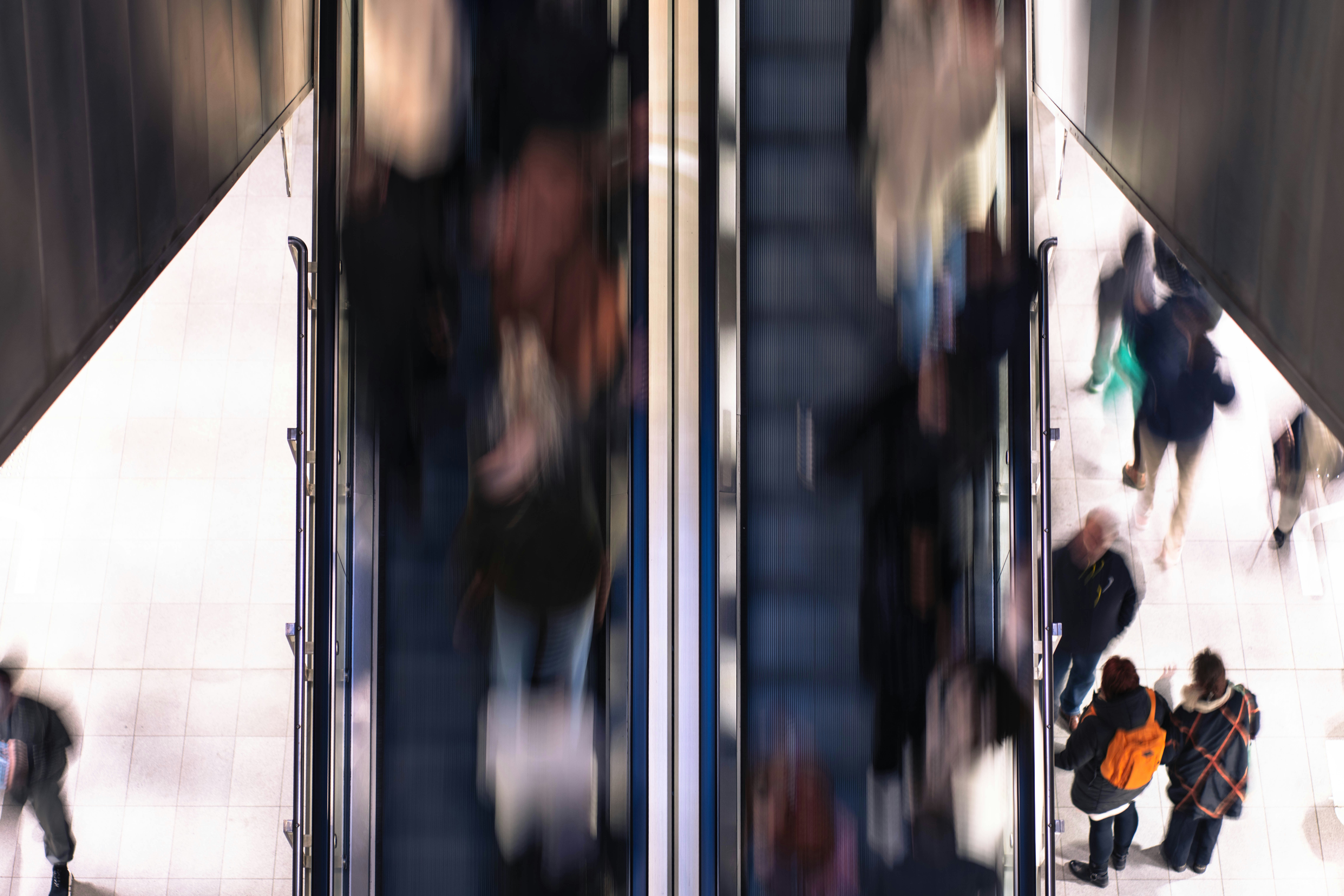Vista borrosa de personas en escaleras mecánicas y pasarelas.