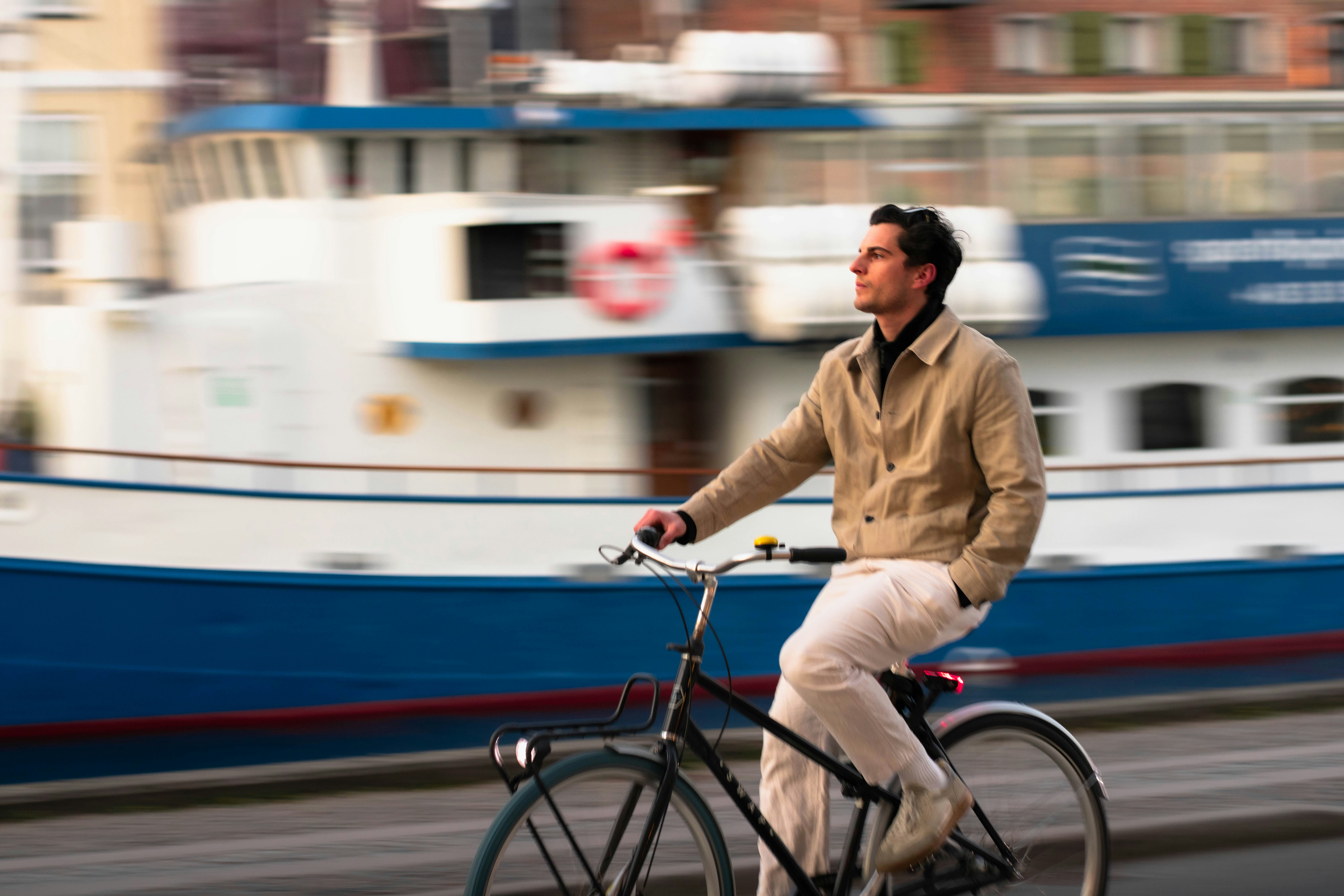 Hombre en bicicleta con un barco de fondo.