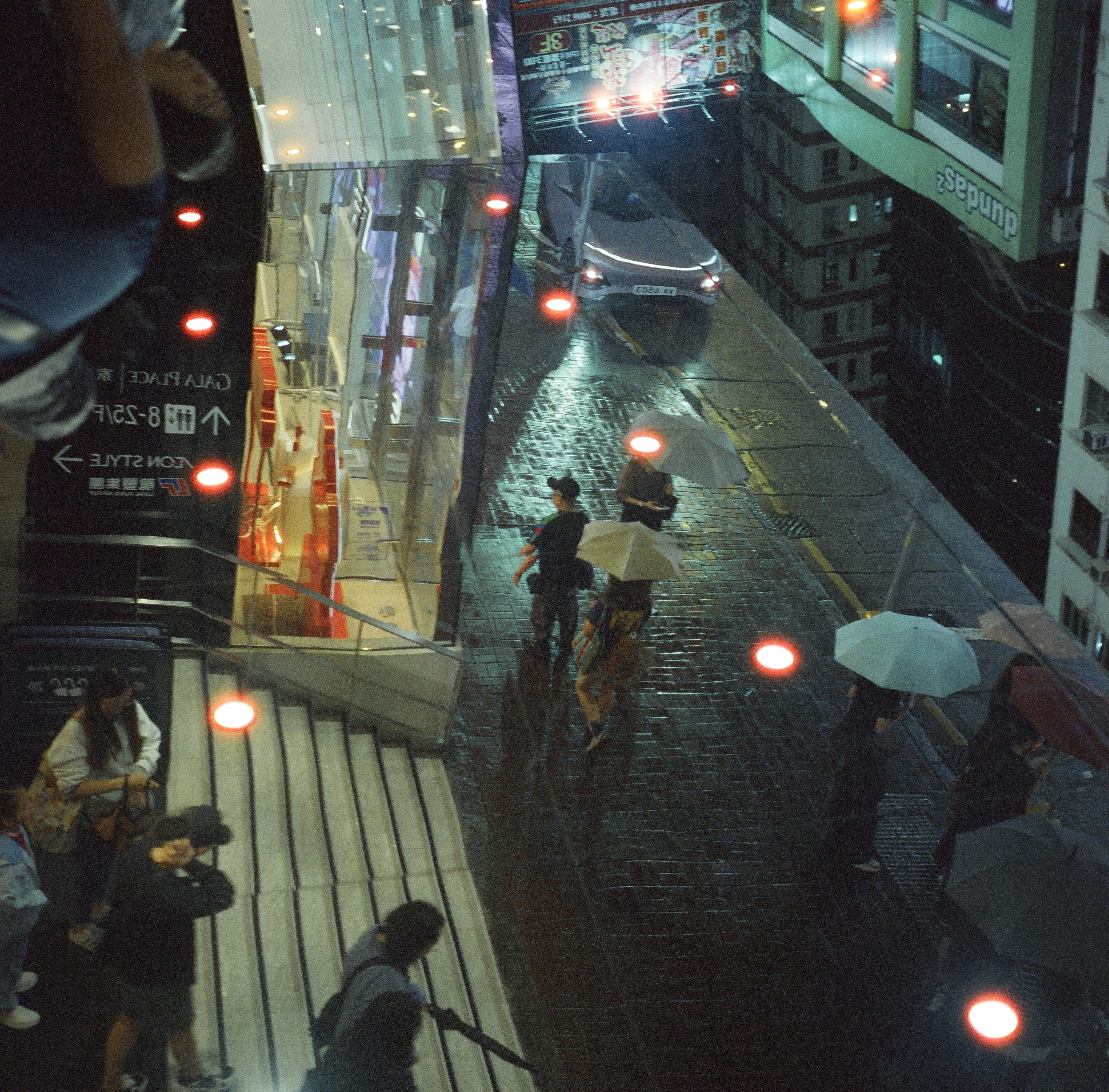 Someone under a black umbrella on a rainy crossing