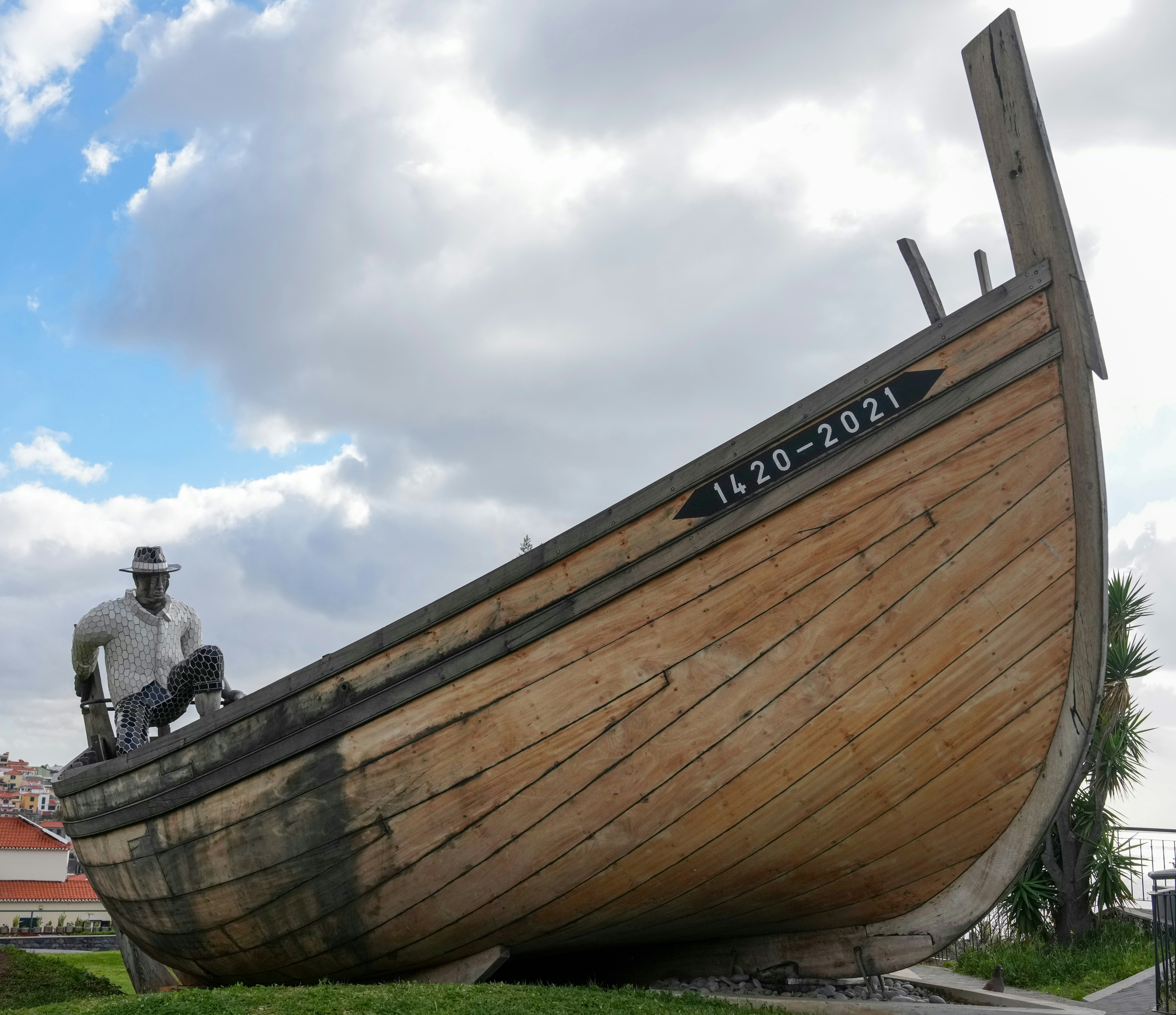Wooden boat sculpture with seated figure and dates