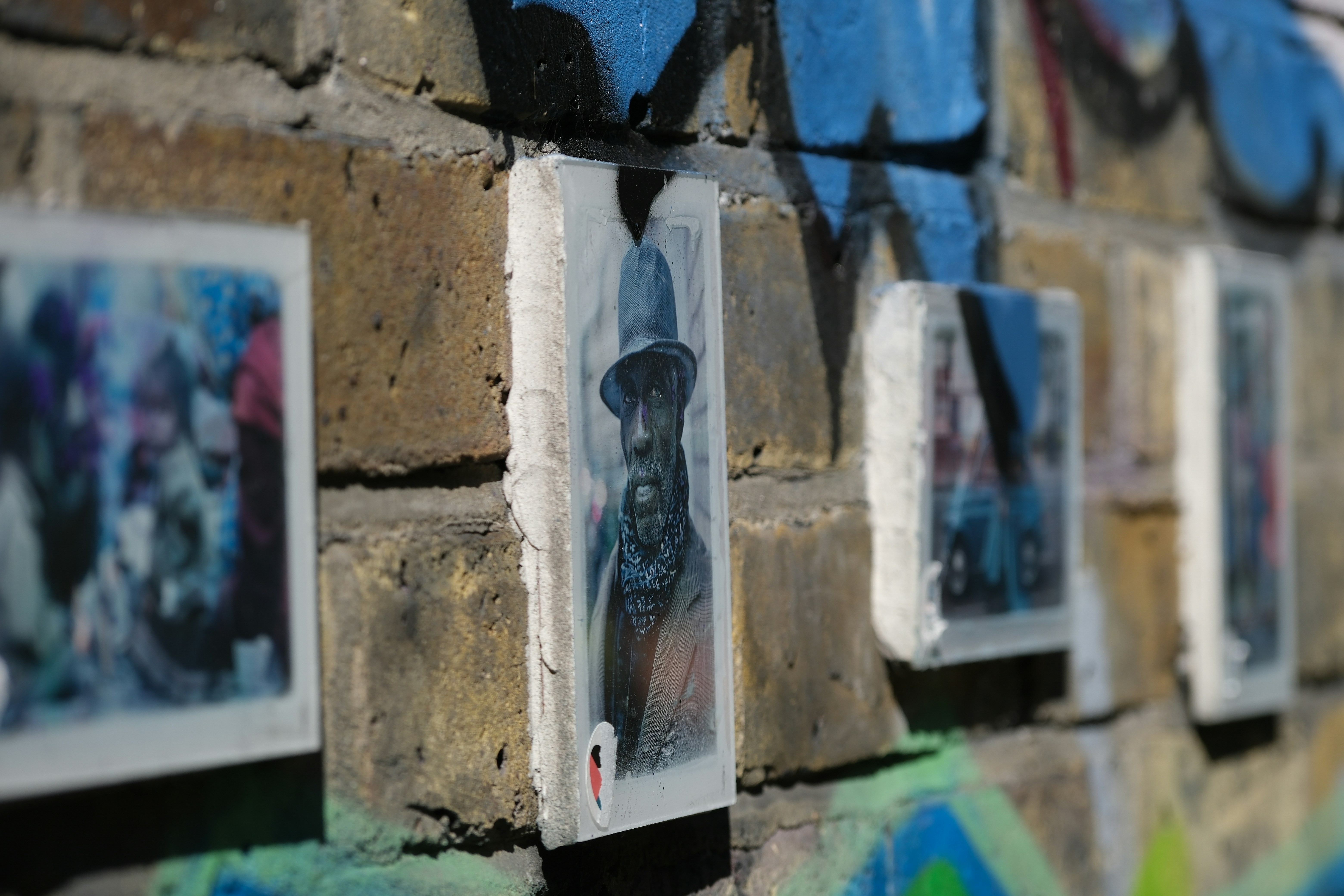 Art graffiti sur un mur de briques avec de petits portraits.