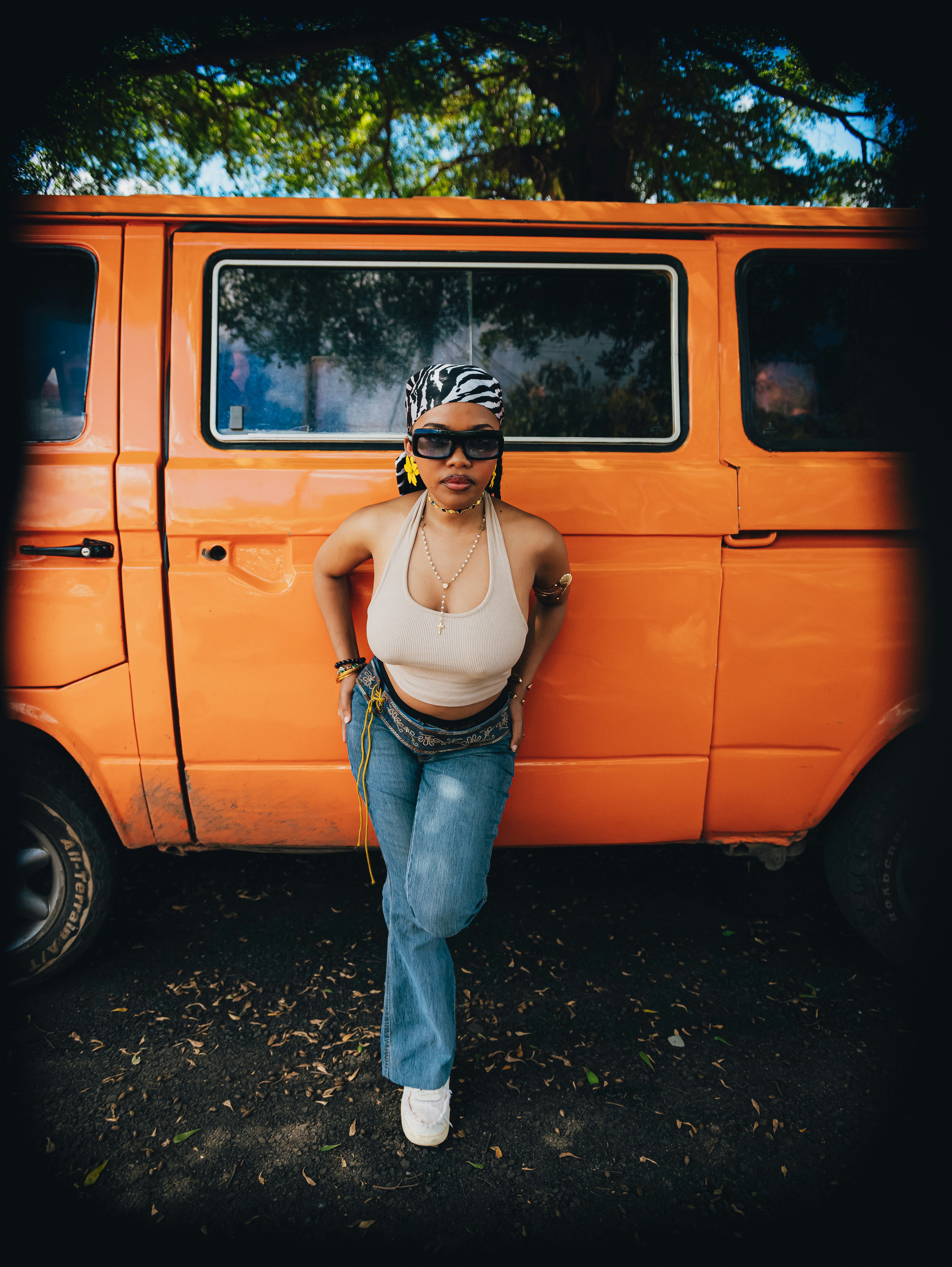 Woman in sunglasses leans against an orange van.