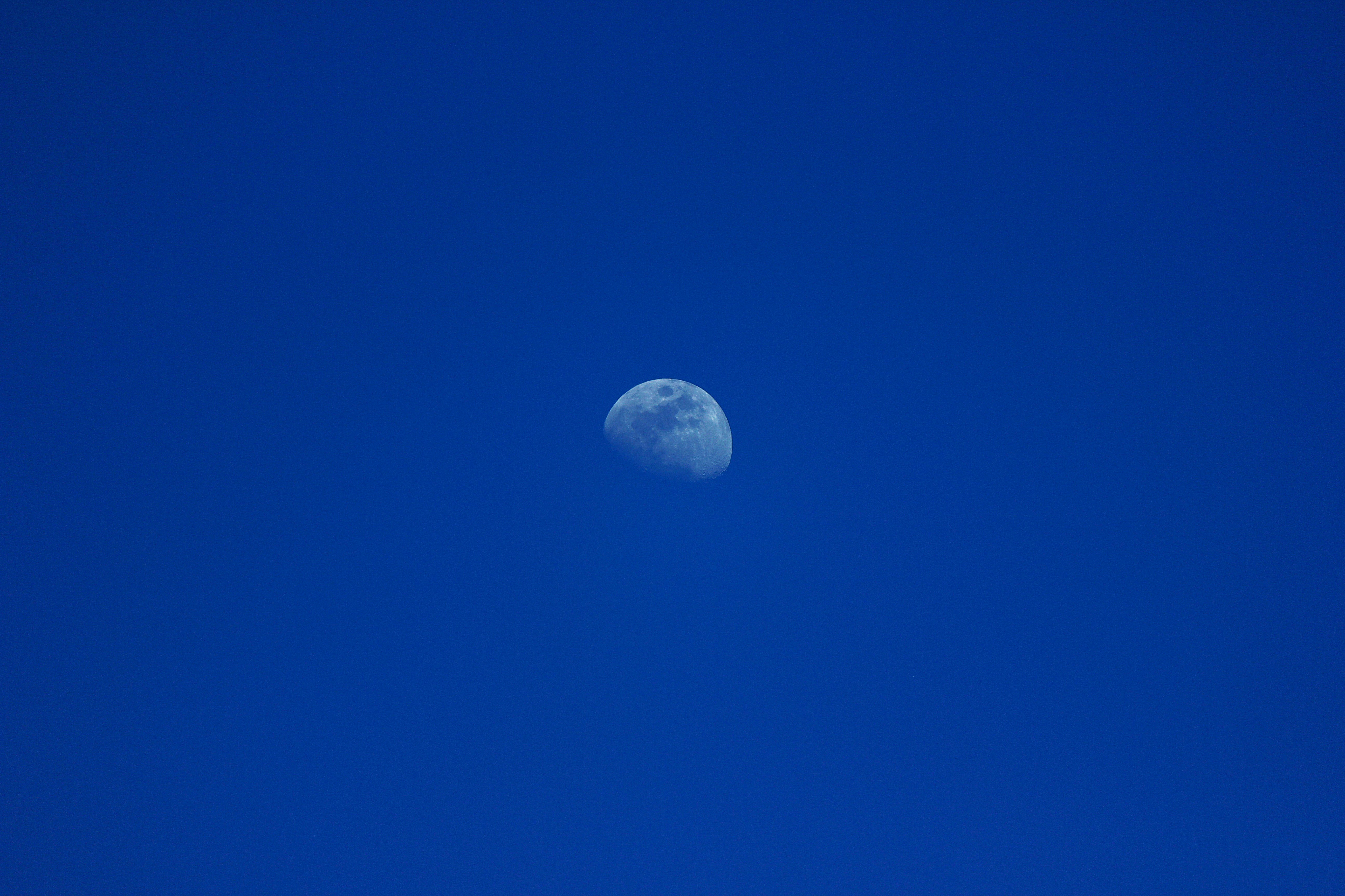 La luna visible en un cielo azul despejado.