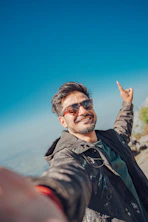 Man in sunglasses points finger up on a sunny day