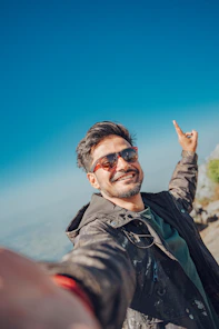 Man in sunglasses points finger up on a sunny day